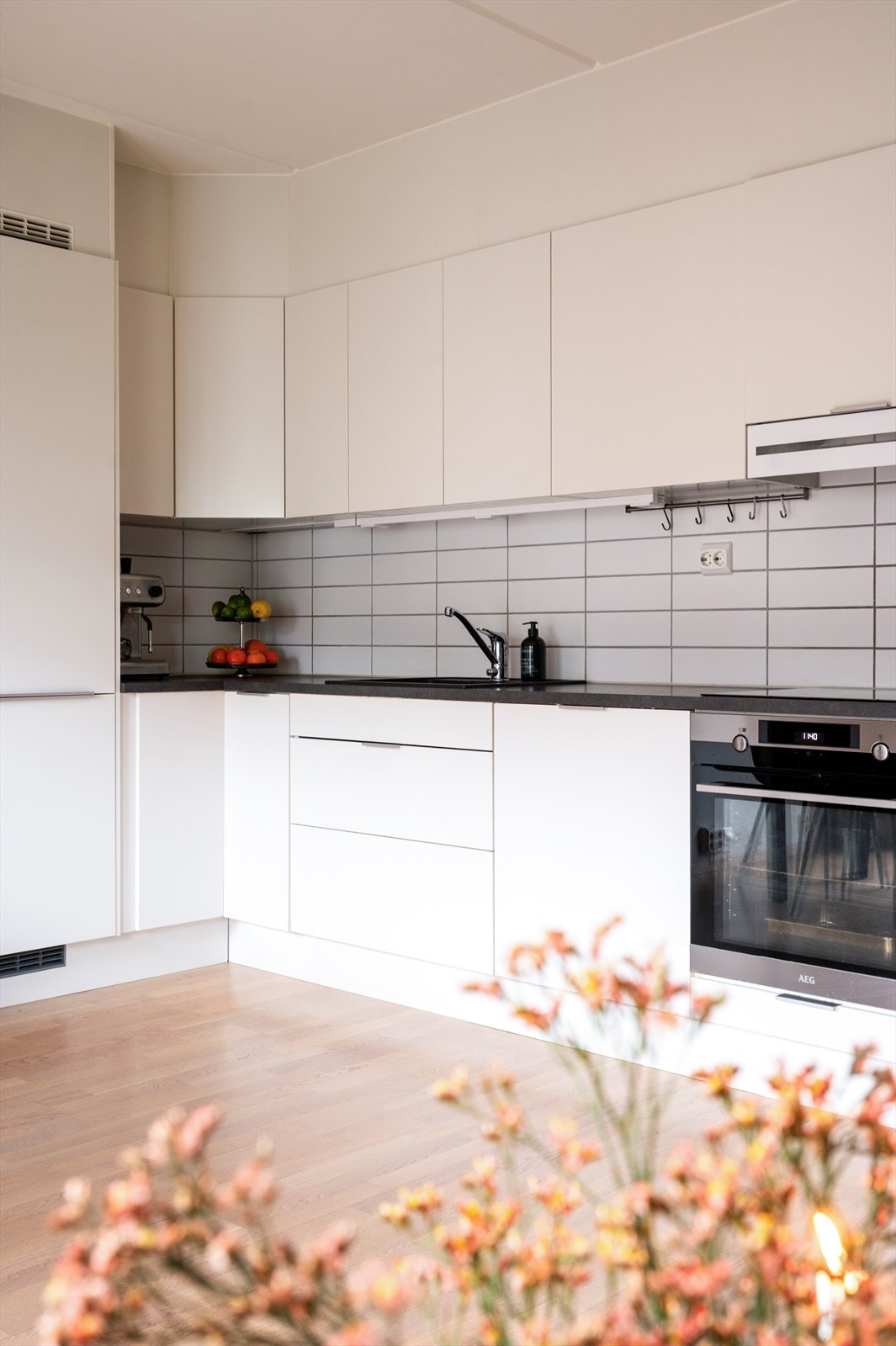 Benkeplate i slitesterk laminat med nedfelt vaskekum, samt fliser og belysning over benk som gir både et funksjonelt og elegant uttrykk Galleribilde