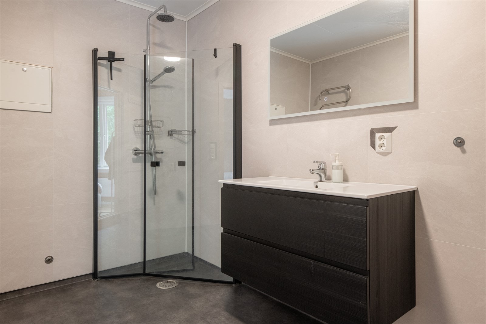 Leiligheten har et romslig bad med et moderne uttrykk. Badet som ligger inntil hovedsoverommet er fra 2021, med belegg på gulv med varmekabler og baderomsplater på veggene. Galleribilde