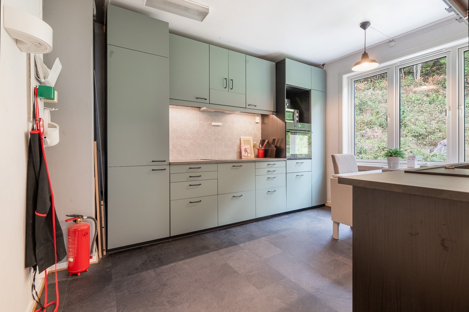 Det delikate kjøkkenet har innredning fra IKEA, med takhøye overskap i sotet glass og øvrig innredning med slette fronter i en dus grønn fargetone. Galleribilde