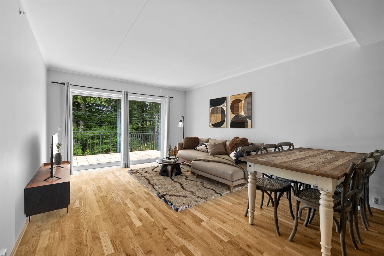 Pen stue med kjøkken i åpen løsning og utgang til balkong - bildet er digitalt møblert Galleribilde