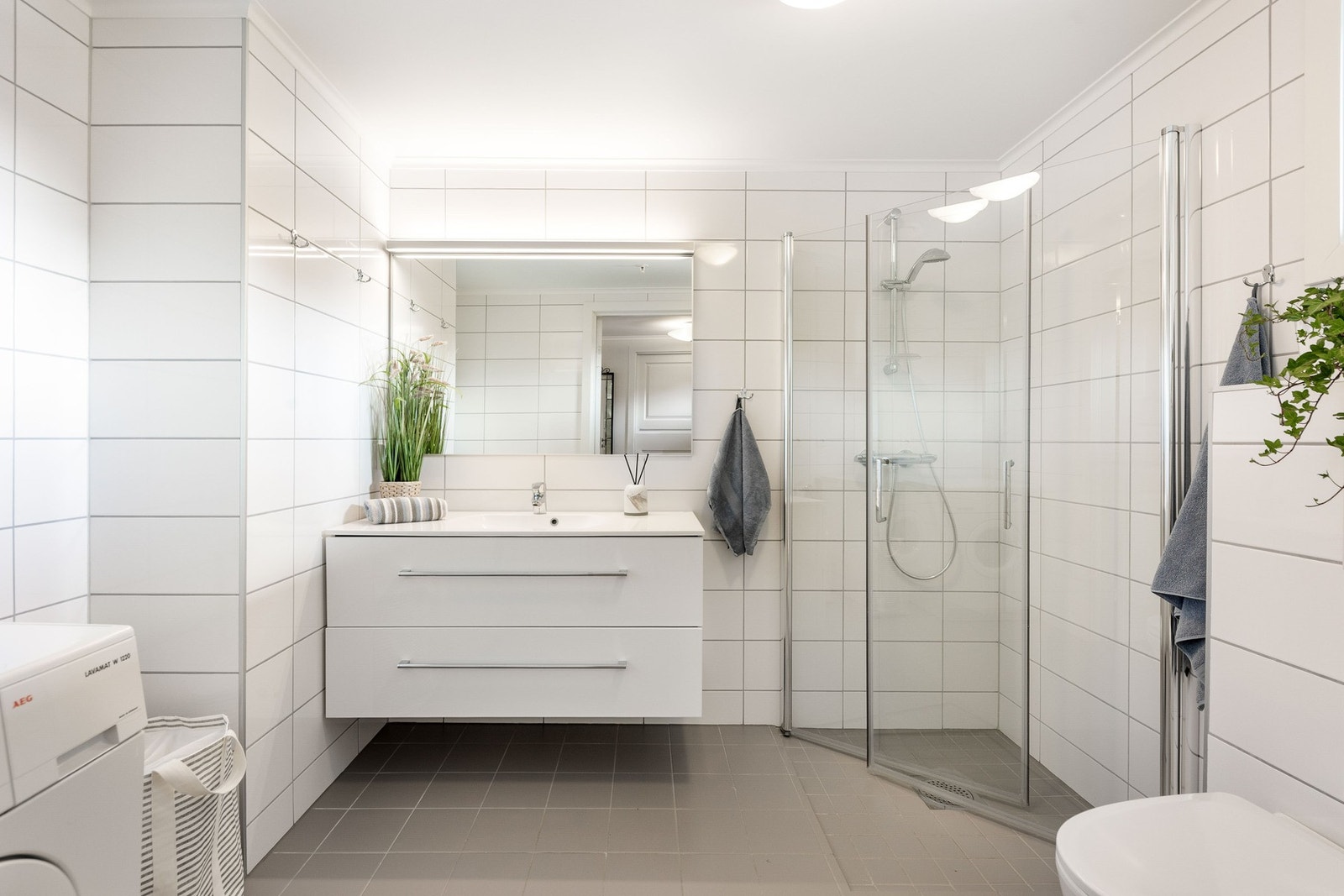 Delikat baderom med dusj, servant med innredning, toalett og opplegg for vaskemaskin. Galleribilde