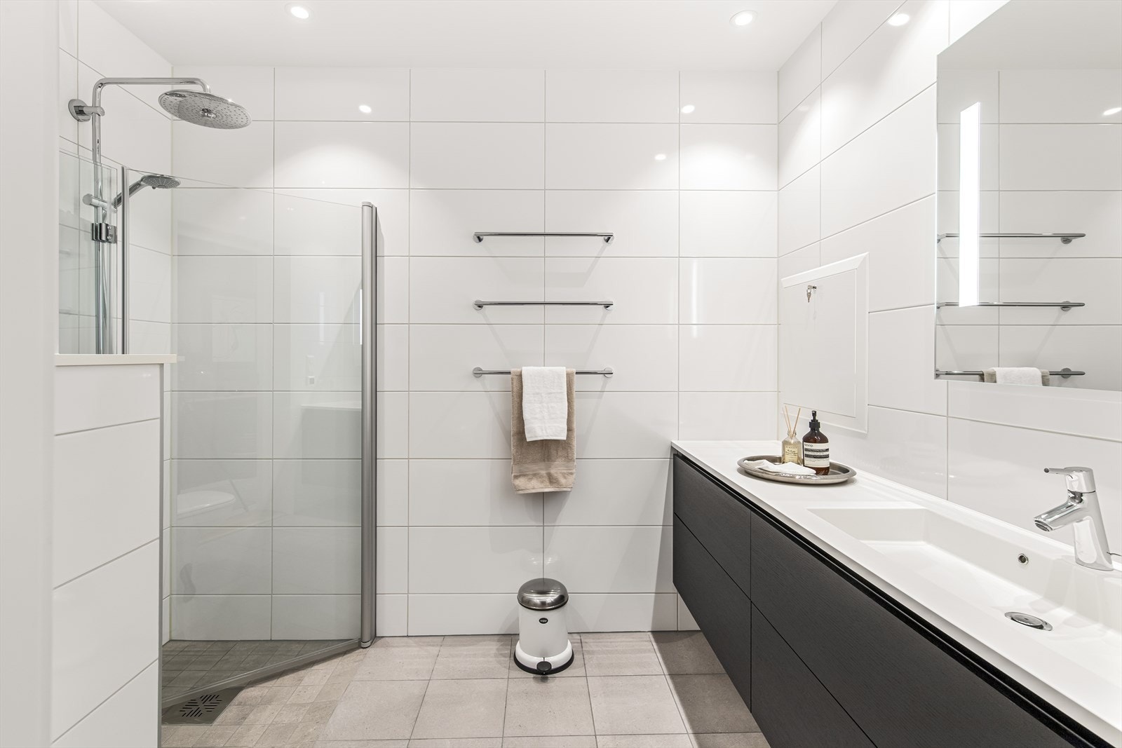 Leiligheten har to delikate bad - det ene med inngang fra entreen, og det andre en del av mastersuiten. Badene har grå fliser på gulv med gulvvarme, hvite fliser på veggene og downlights i himling. Galleribilde