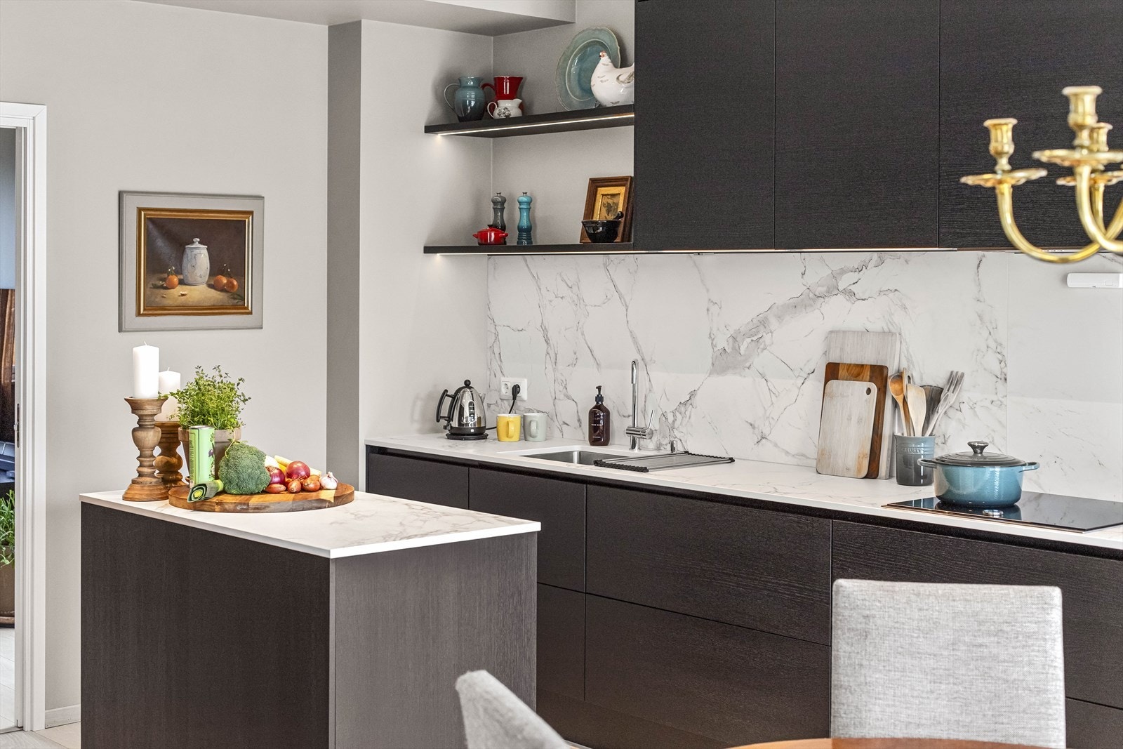 Kjøkkenet har integrert kombiovn, stekeovn, induksjonstopp, oppvaskmaskin, kjøleskap og kullfilterventilator. Det er rikelig med oppbevaringsplass i skap og dype kolonialskuffer, og god arbeidsflyt med både benk og øy. Galleribilde