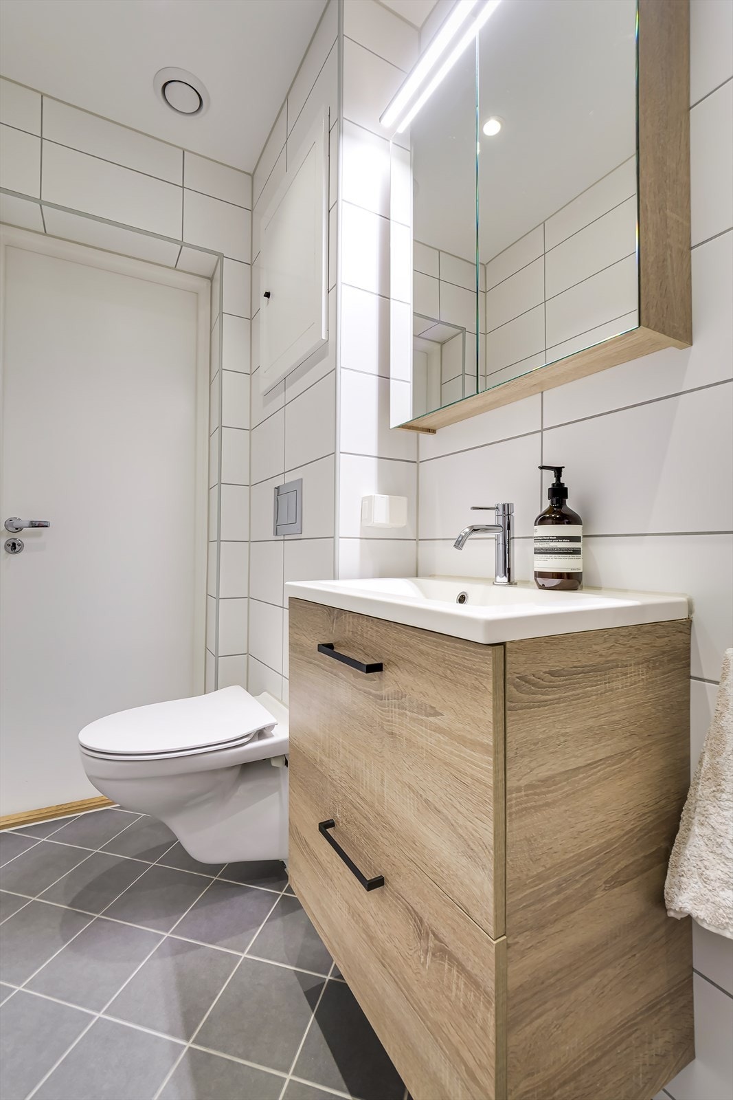 Badet er innredet med vegghengt klosett, servant nedfelt i innredning, speilskap og dusjhjørne med svingbare foldedører av glass. Galleribilde