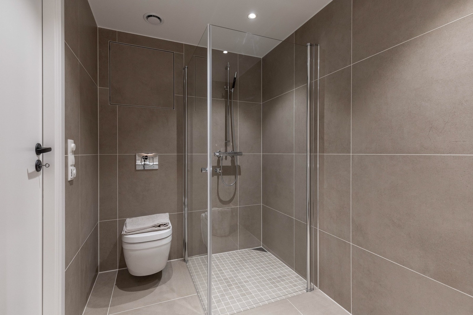 Leiligheten har to moderne bad, begge med store grå fliser, gulvvarme og downlights i himlingen. Det ene ligger tilknyttet hovedsoverommet i en suiteløsning. Galleribilde