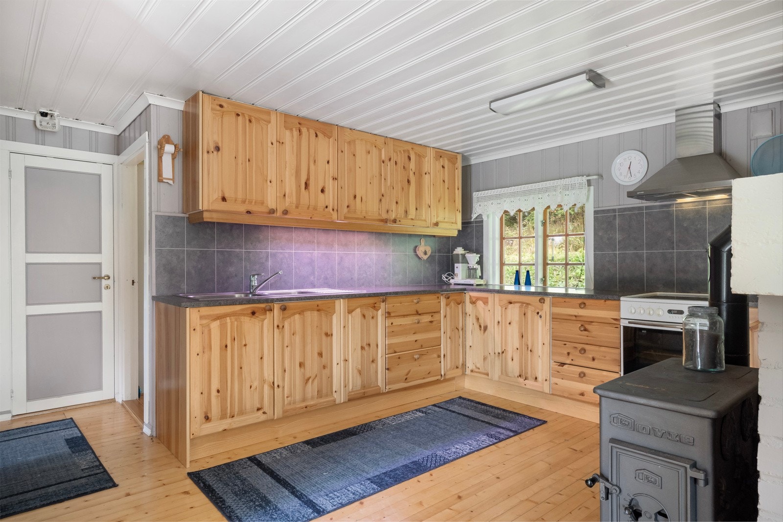 Kjøkkenet har innredning ivinkel og plass til komfyr og kjøleskap. Galleribilde