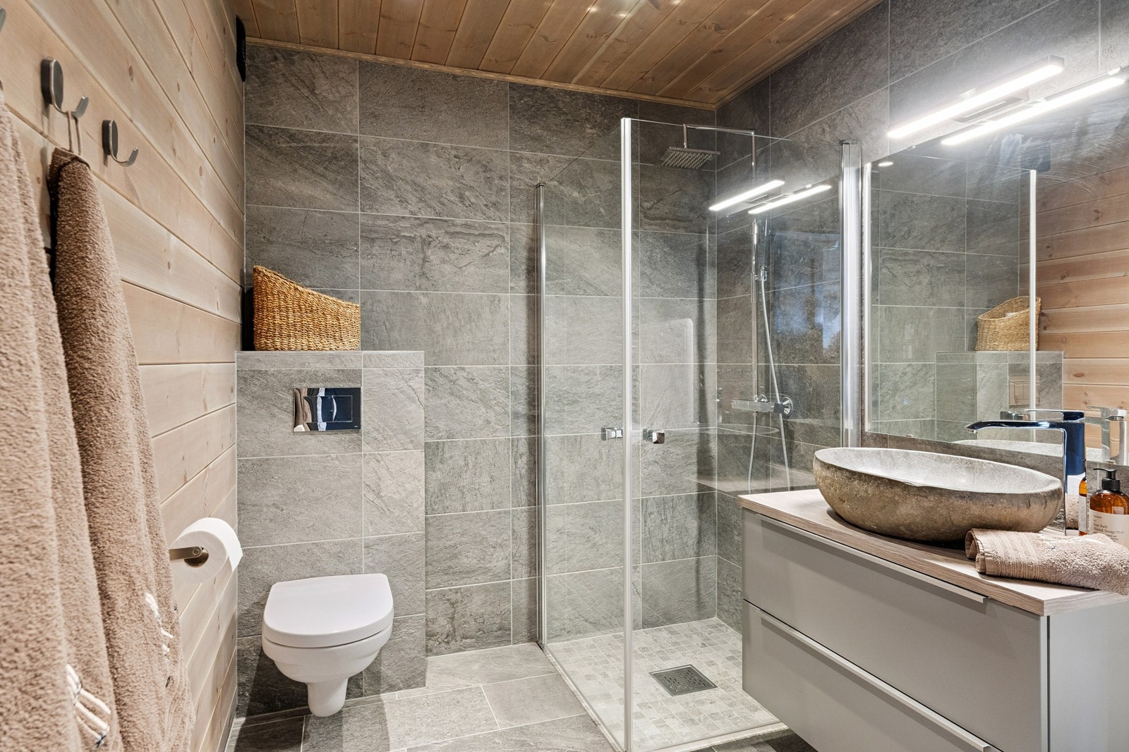 Badet har flislagt gulv og dusjløsning i hjørnet Galleribilde