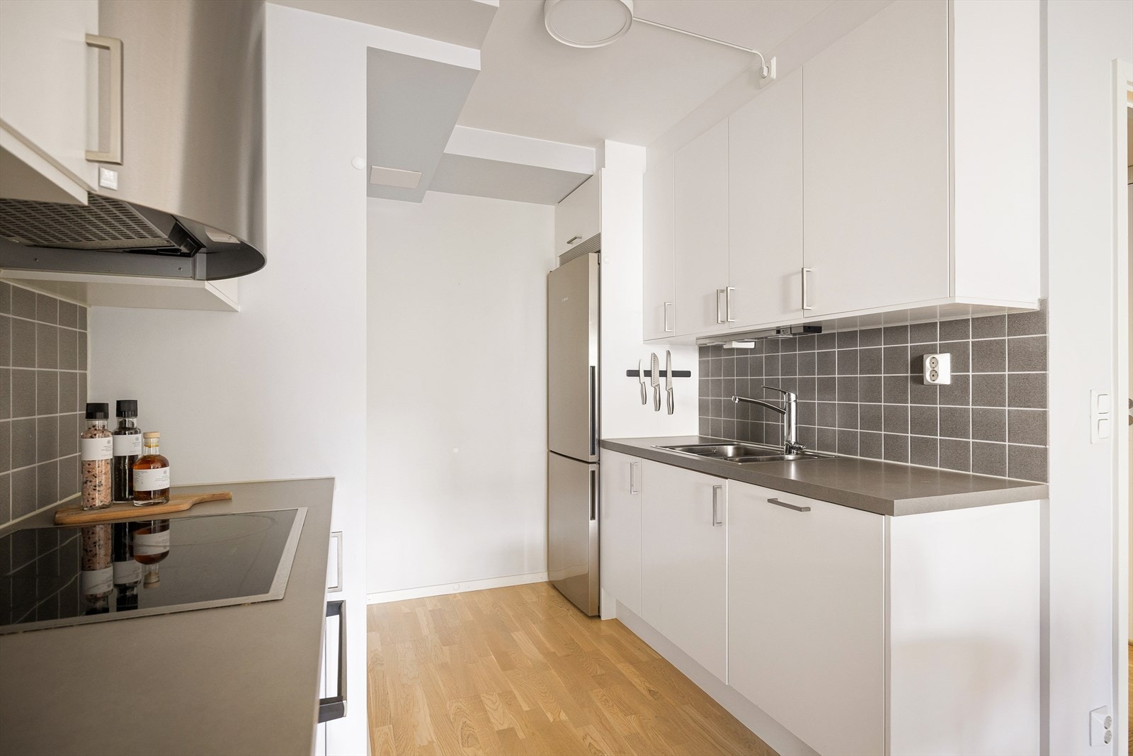 Kjøkkeninnredningen fra 2014 består av hvite, glatte fronter, fliser på vegg over kjøkkenbenk og benkeplate av laminat. Galleribilde