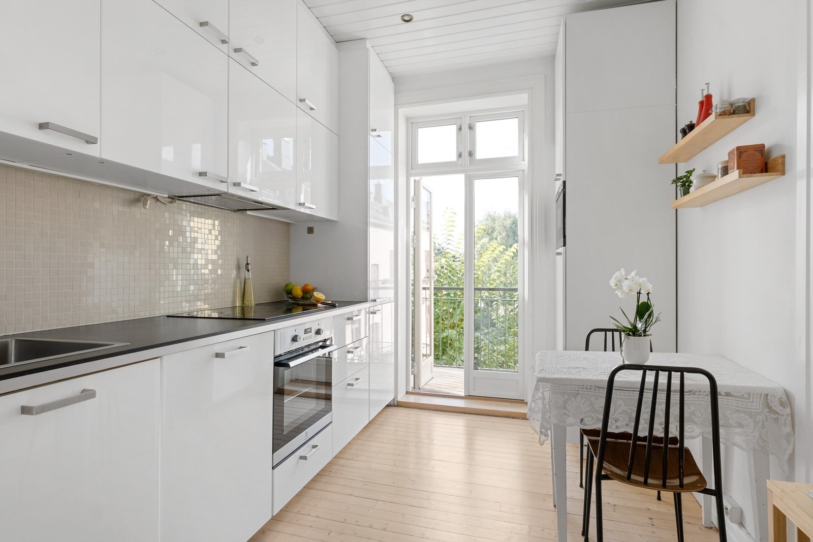 - Kjøkkeninnredning med glatte fronter, laminat benkeplate med nedfelt vaskekum, samt fliser og belysning over benkeplaten - Galleribilde