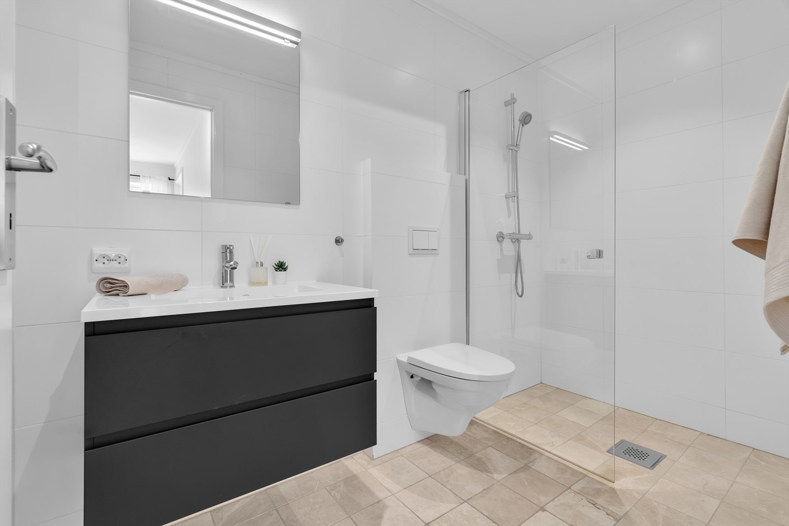 Flislagt bad med dusjnisje, veggmontert toalett og heldekkende servant i baderomsinnredning Galleribilde