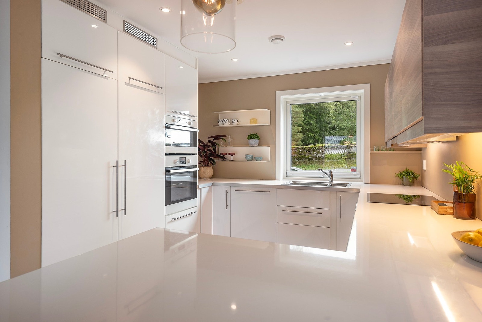 Et stilrent og moderne kjøkken med glatte fronter og overskap i harmoniske farger som sømløst glir inn i veggen for et helhetlig uttrykk Galleribilde