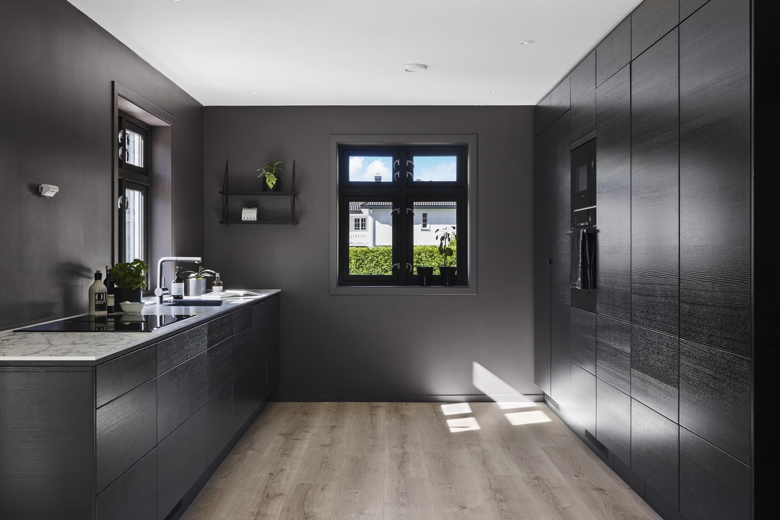 Stilren og moderne innredning, nytt i 2024, med slette sorte fronter på underskap, skuffer og høyskap Galleribilde