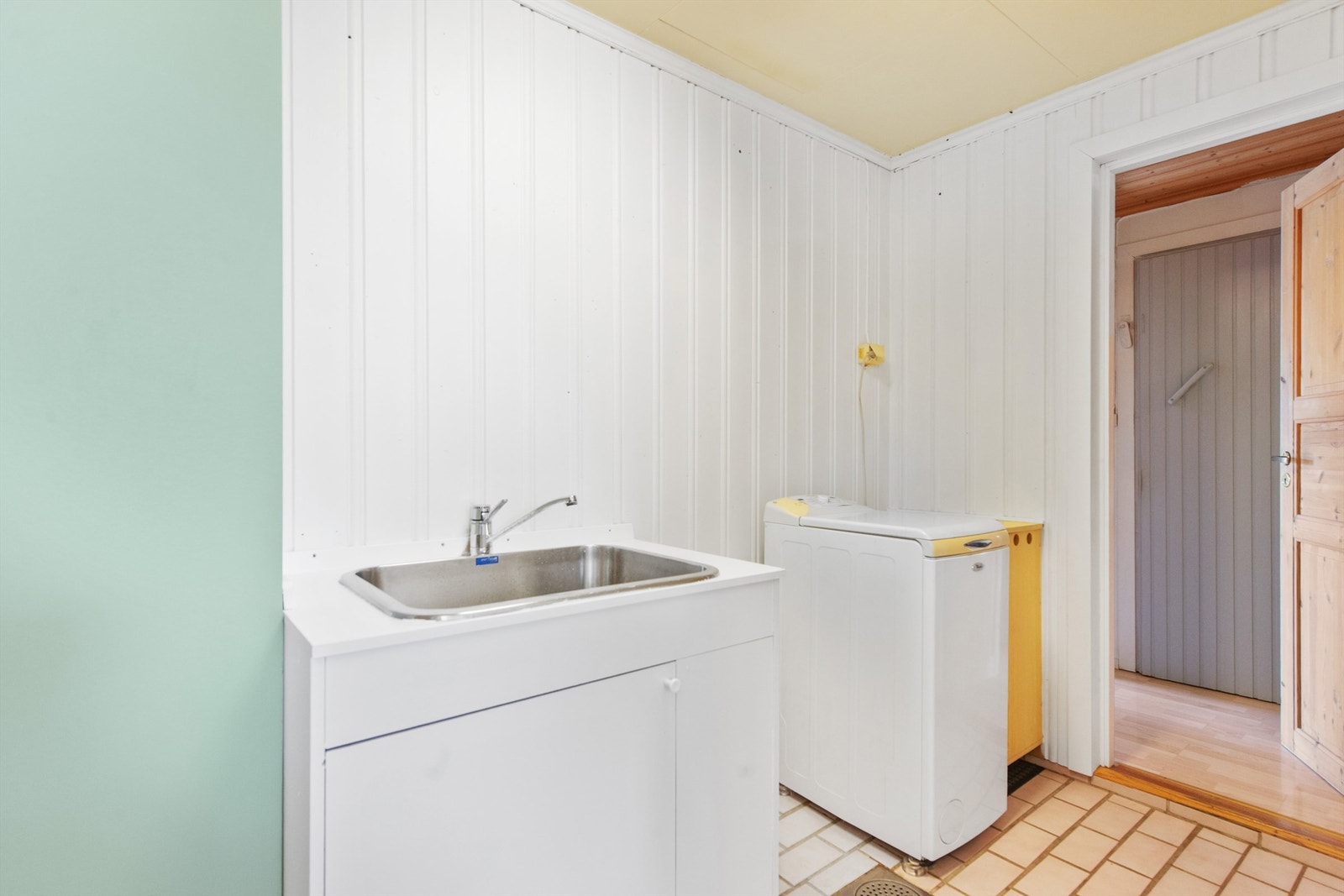 Praktisk vaskeromsdel med utslagsvask og plass til vaskemaskin og tørketrommel. Galleribilde