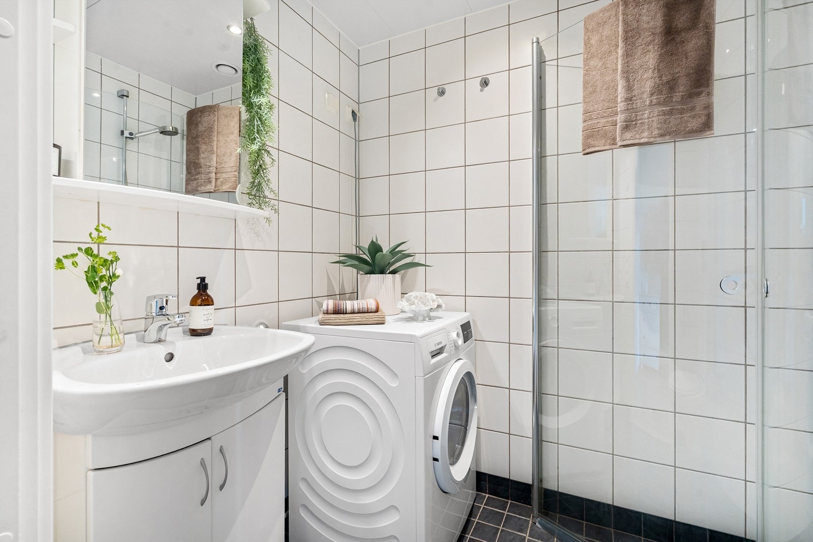 Badet har elektrisk gulvvarme og er ellers utstyrt med servantskap med nedfelt servant med 1-greps blandebatteri og underskap, cusjhjørne med glassdører, vegghengt toalett og opplegg for vaskemaskin. Galleribilde