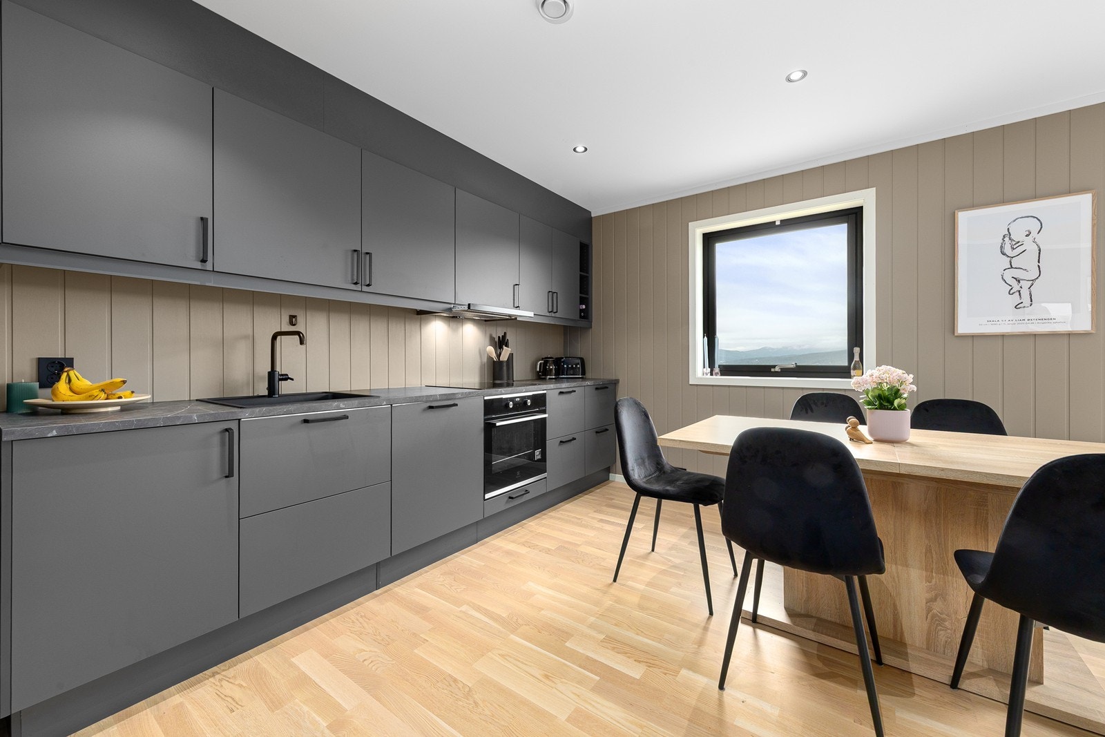 Delikat kjøkkeninnredning med slette fronter i sort utførelse. Kjøkkenet inneholder integrert komfyr, platetopp og oppvaskmaskin. Galleribilde