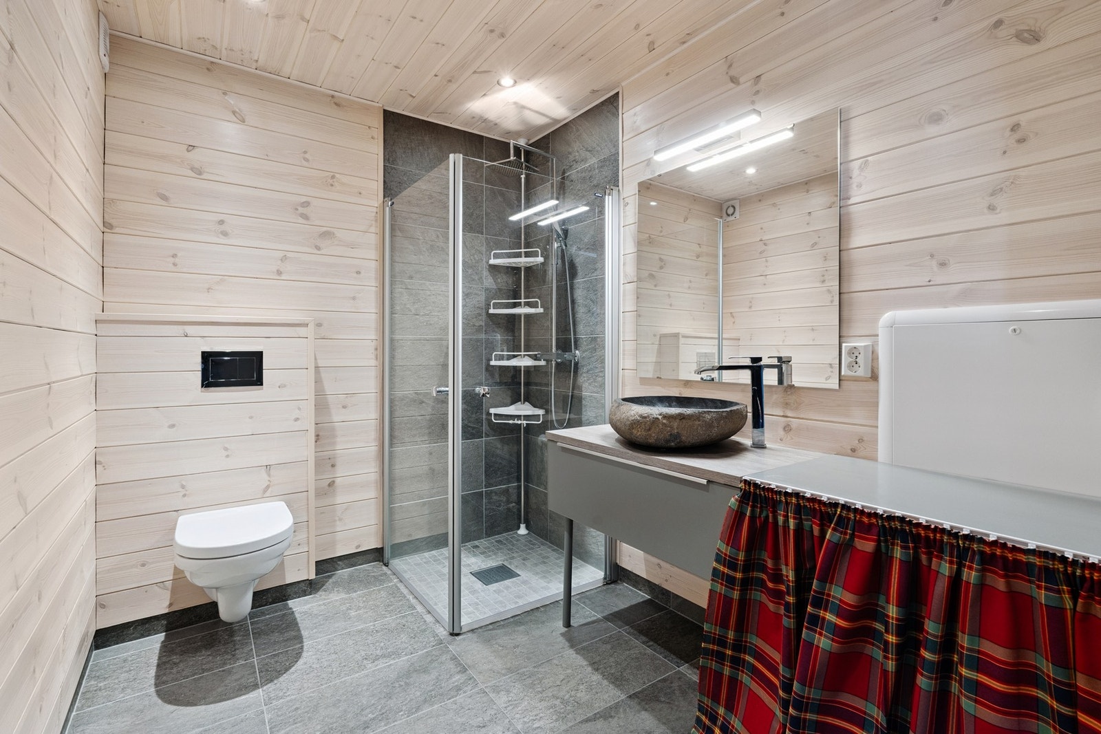 Badet er pent innredet med moderne fliser på gulv og i dusjsonen Galleribilde