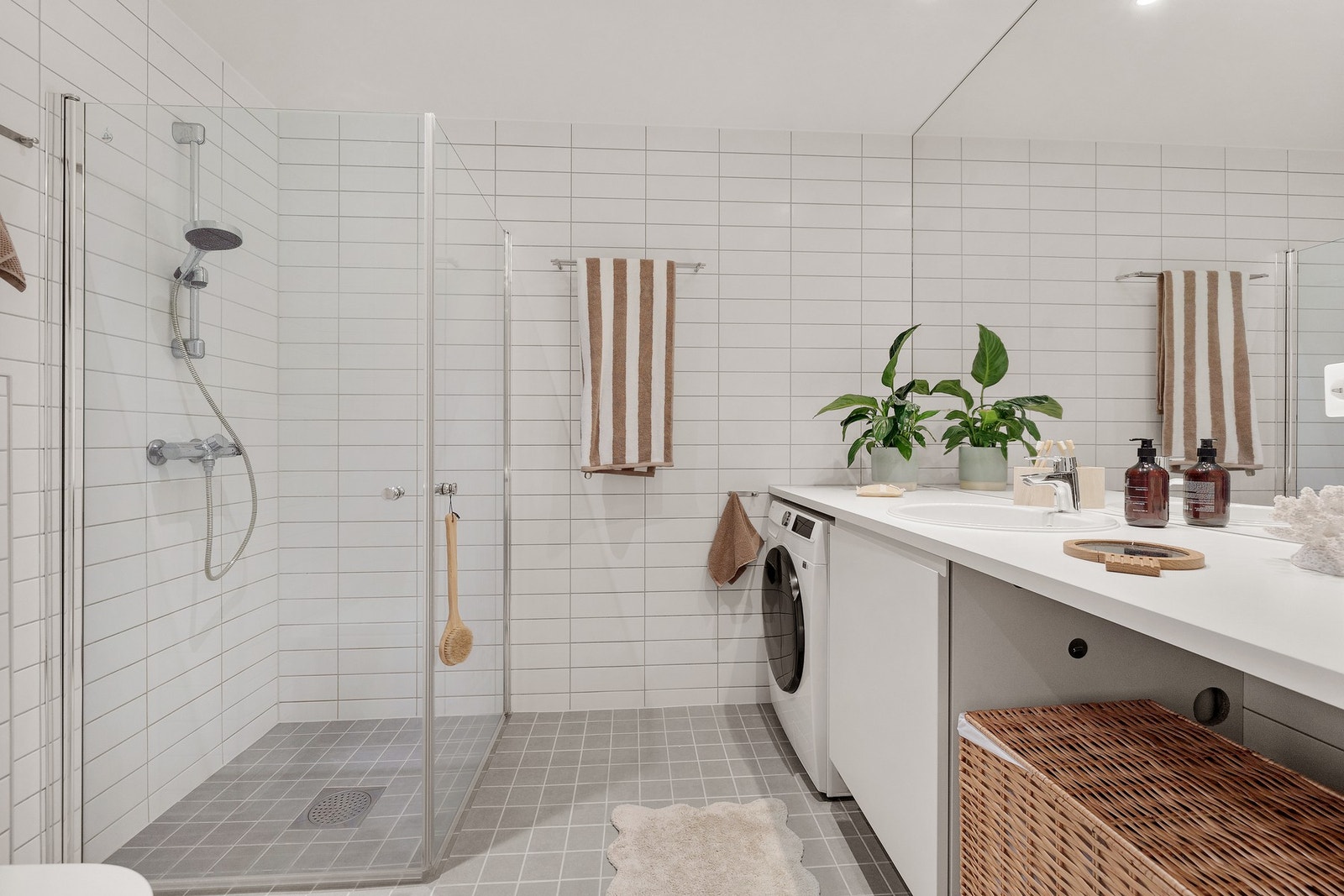 Stort og lekkert bad med opplegg for vaskemaskin, innfellbare dusjdører, vegghengt WC, servant, speil og skap. Galleribilde