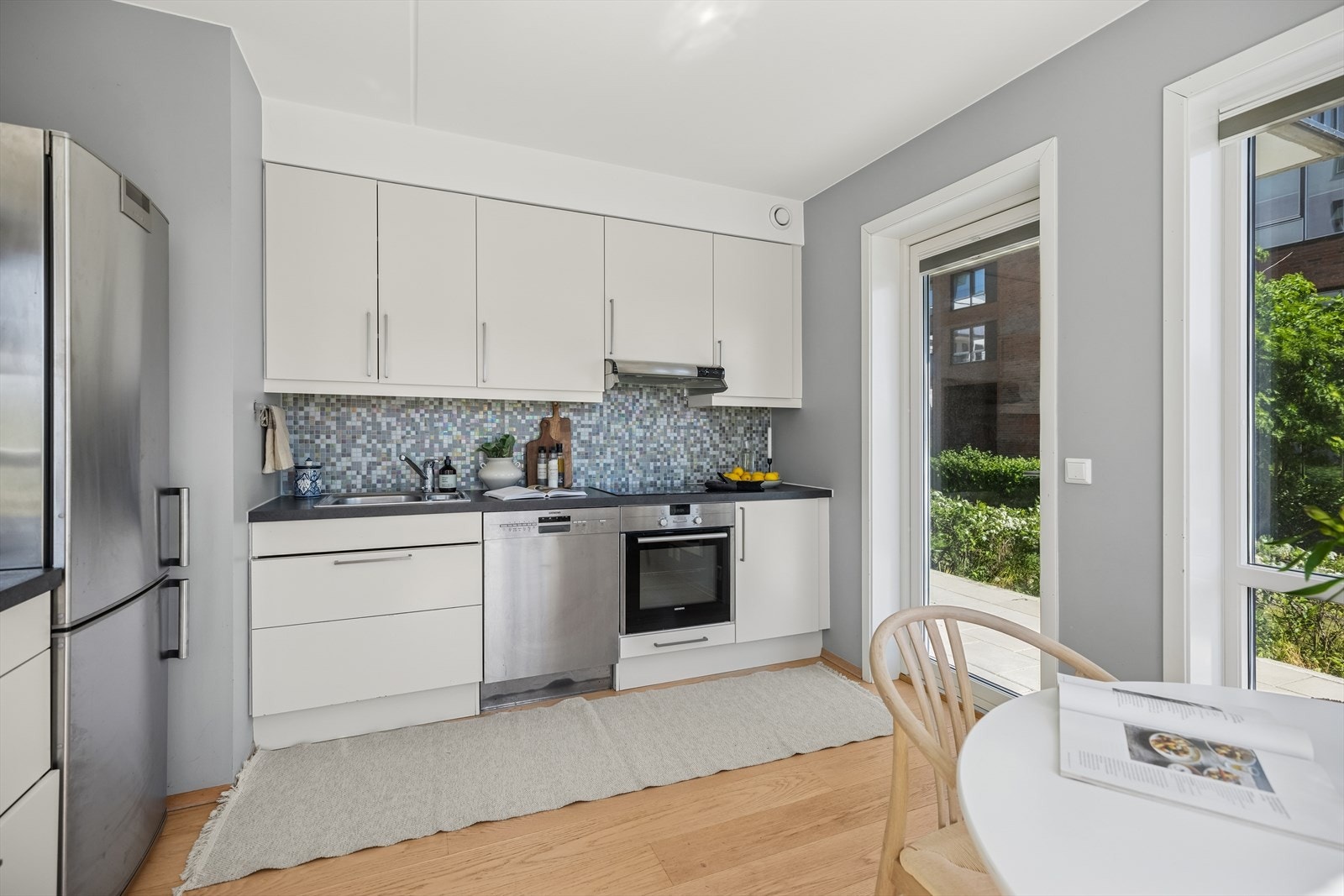 Kjøkkenet er praktisk tilrettelagt med opplegg for oppvaskmaskin, og har integrerte hvitevarer som induksjonstopp, stekeovn og mikrobølgeovn - sømløst innpasset i innredningen. Galleribilde