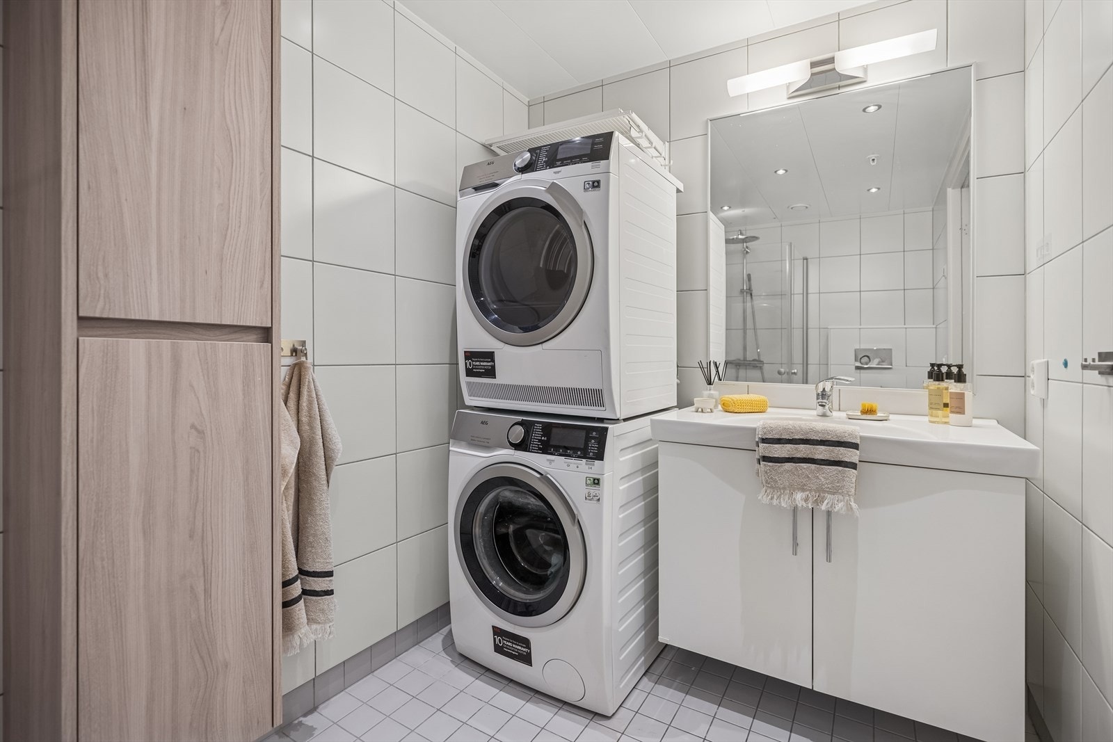 Baderomsinnredning bestående av benkeskap med glatte fronter. Speil og belysning over servant. Galleribilde