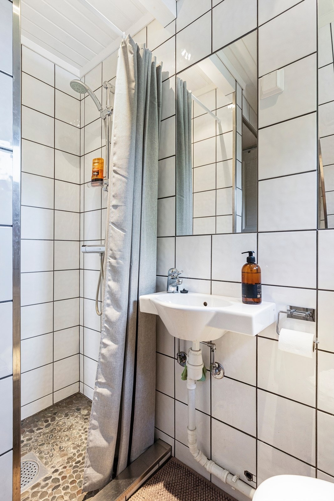Badet er fra starten av 2000-tallet og har fliser på vegg, panel i himling og flislagt gulv med varmekabler. Rommet er utstyrt med servant, toalett og dusjhjørne. Galleribilde