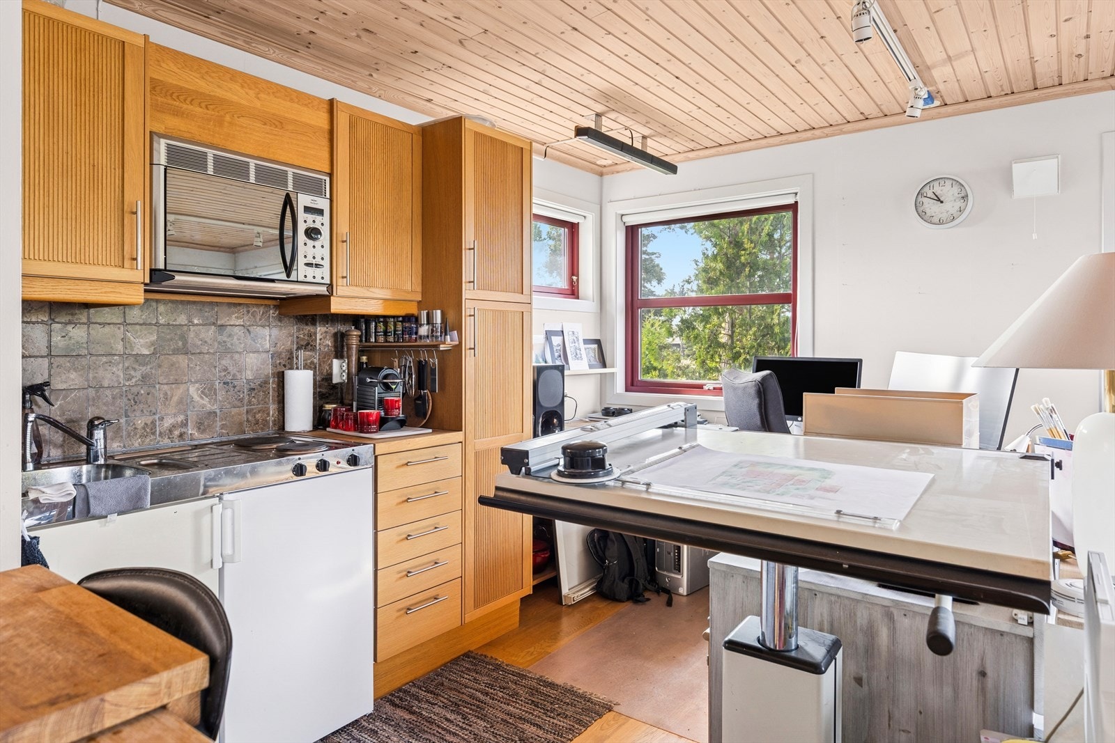 Innredning med fronter i eik heltre, profilerte fyllinger i skap og slette fronter i skuffer, med stål bøylehåndtak. Kjøkkenet har en hybelkjøkken-modul med platetopp, kjøleskap og vask. Galleribilde