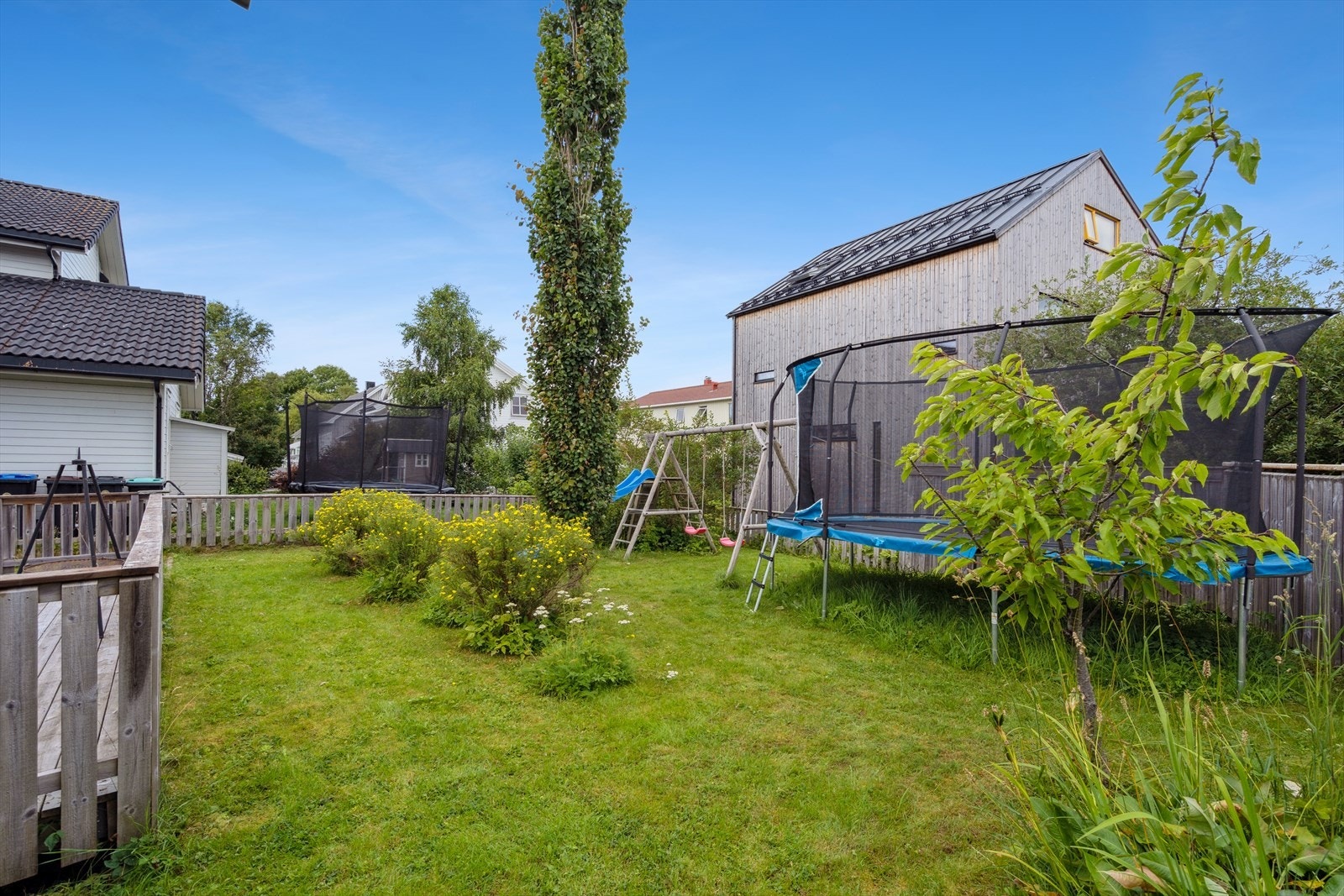 Flott inngjerdet hage med gressplen og diverse beplantning Galleribilde