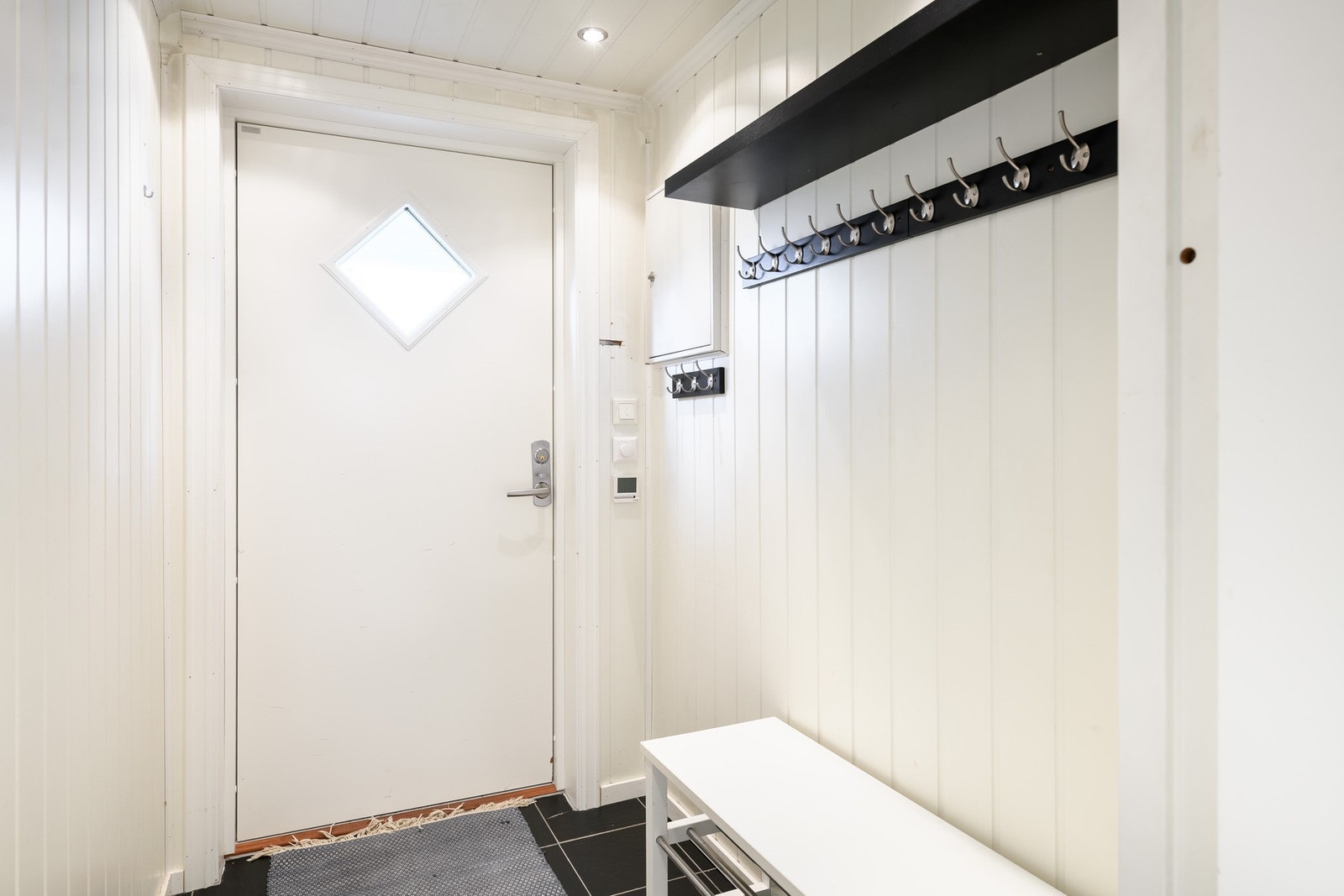 Leiligheten fikk ny ytterdør i 2024, og i entreen er det elektrisk varme i flislagt gulv. Galleribilde