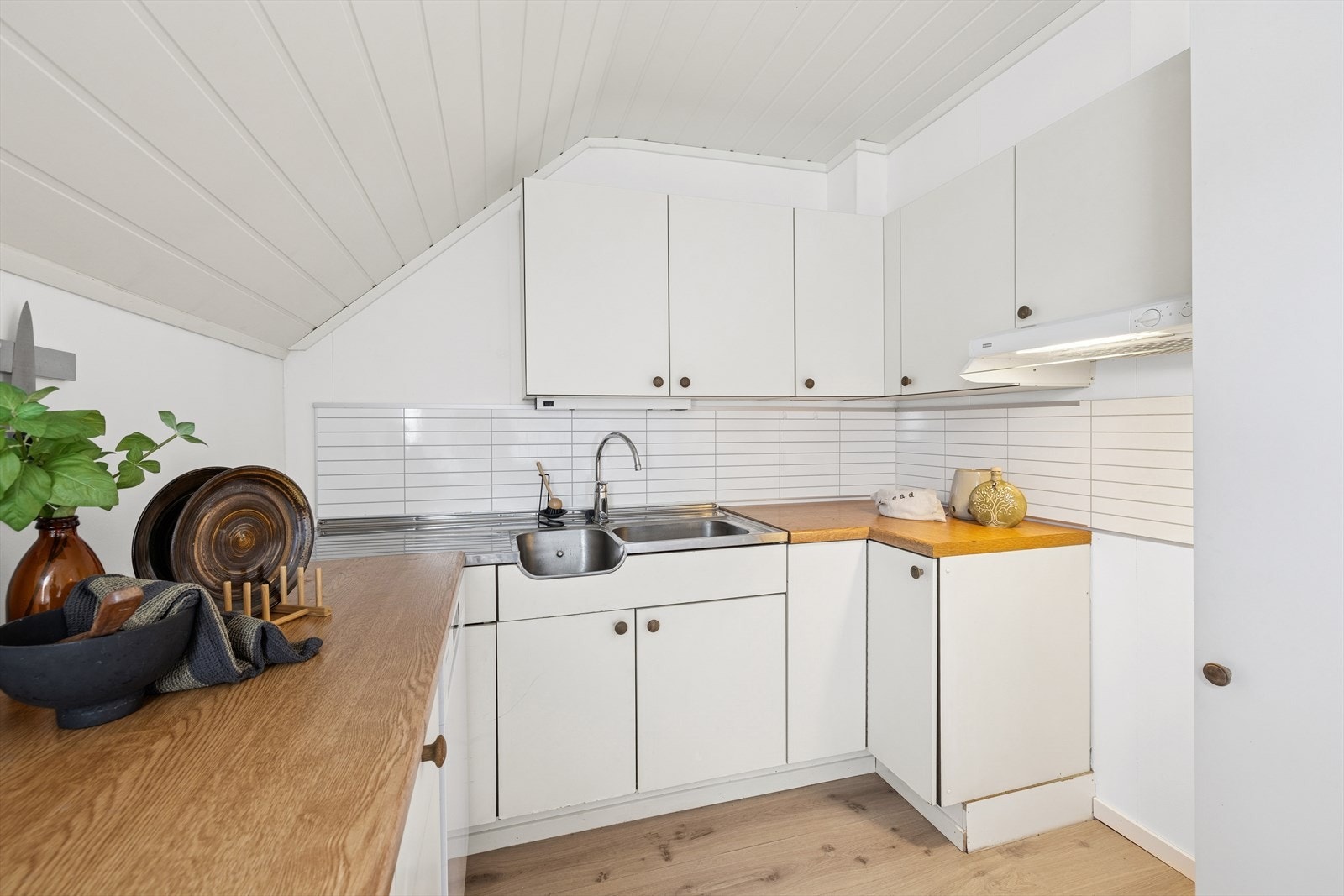 Den praktiske benkeplaten i laminat gir rikelig arbeidsflate, og kjøkkenvasken med to kummer og avrenningsfelt gjør oppvask både enkelt og effektivt Galleribilde