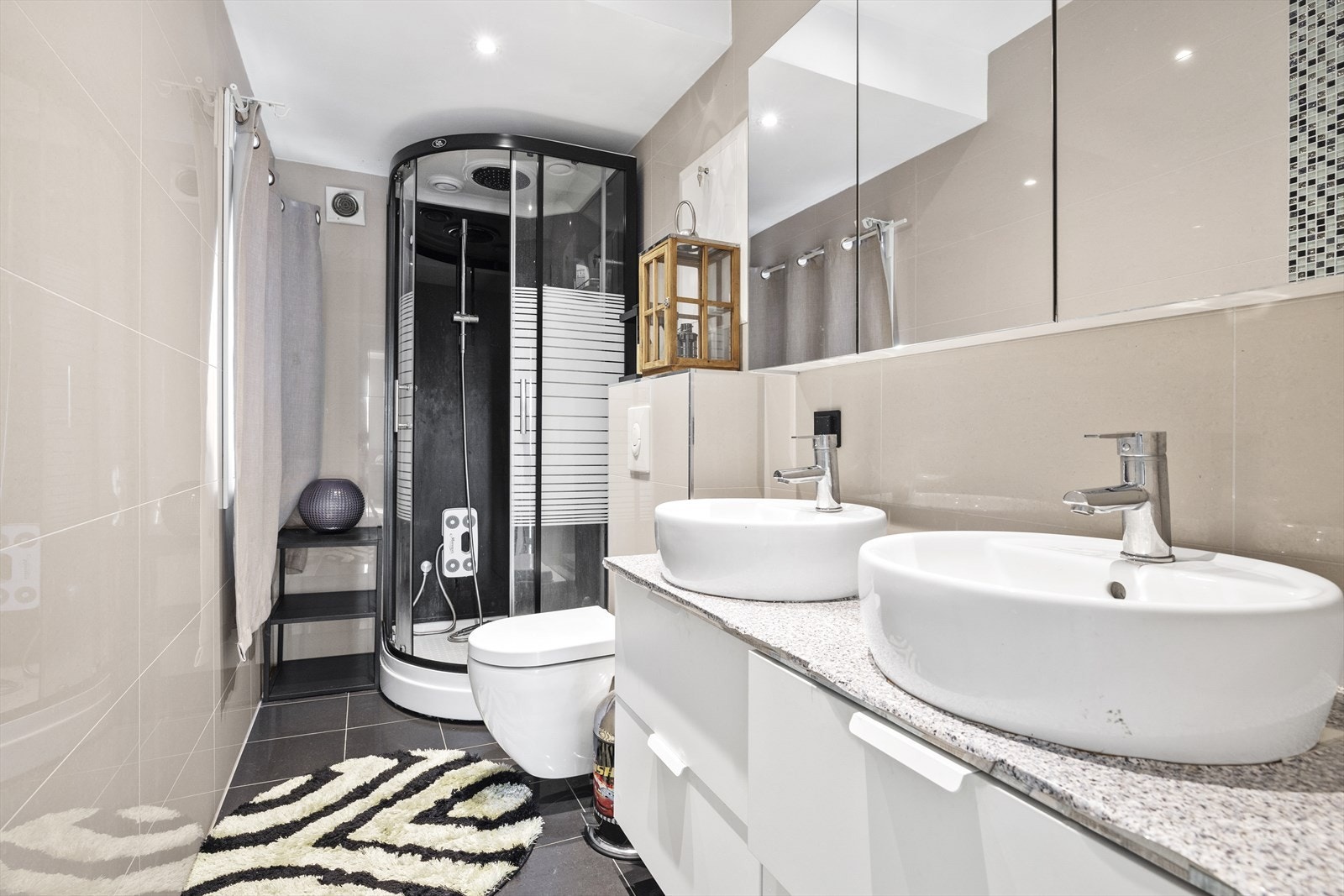 Lekkert baderom som ble pusset opp i 2018/2019. Baderomsinnredningen består av benkeskap med glatte fronter, laminat benkeplate, veggskap med speilfronter over servant, dusjkabinett, to servanter og veggfestet klosett. Galleribilde