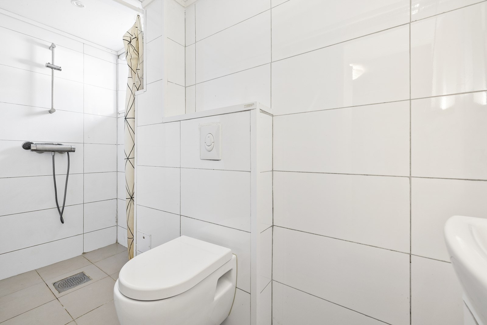 Flislagt baderom som ble pusset opp i 2018/2019. Badet er innredet med benkeskap med glatte fronter, dusj på gulv, servant og veggfestet klosett med innebygget sisterne. Galleribilde