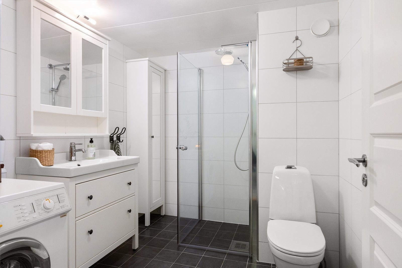 Boligen har et moderne, flislagt bad med dusjhjørne med glassvegger, servant med underskap og vegghengt speilskap. Badet har frittstående toalett og varmekabler i gulvet som gir ekstra komfort. Galleribilde