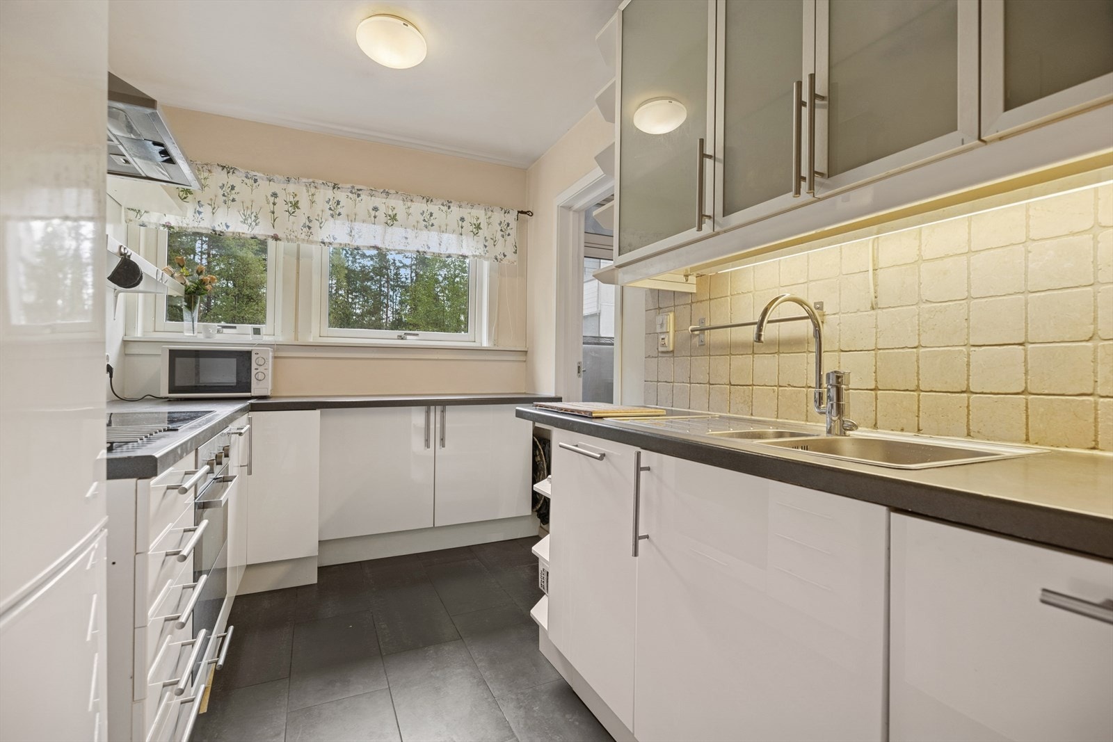 Benkeplatene er i laminat, og over benken er det lagt fliser samt malte flater som gir en tidløs og praktisk løsning. Det er nedfelt oppvaskkum med skyllekum i rustfritt stål og ettgreps blandebatteri. Galleribilde