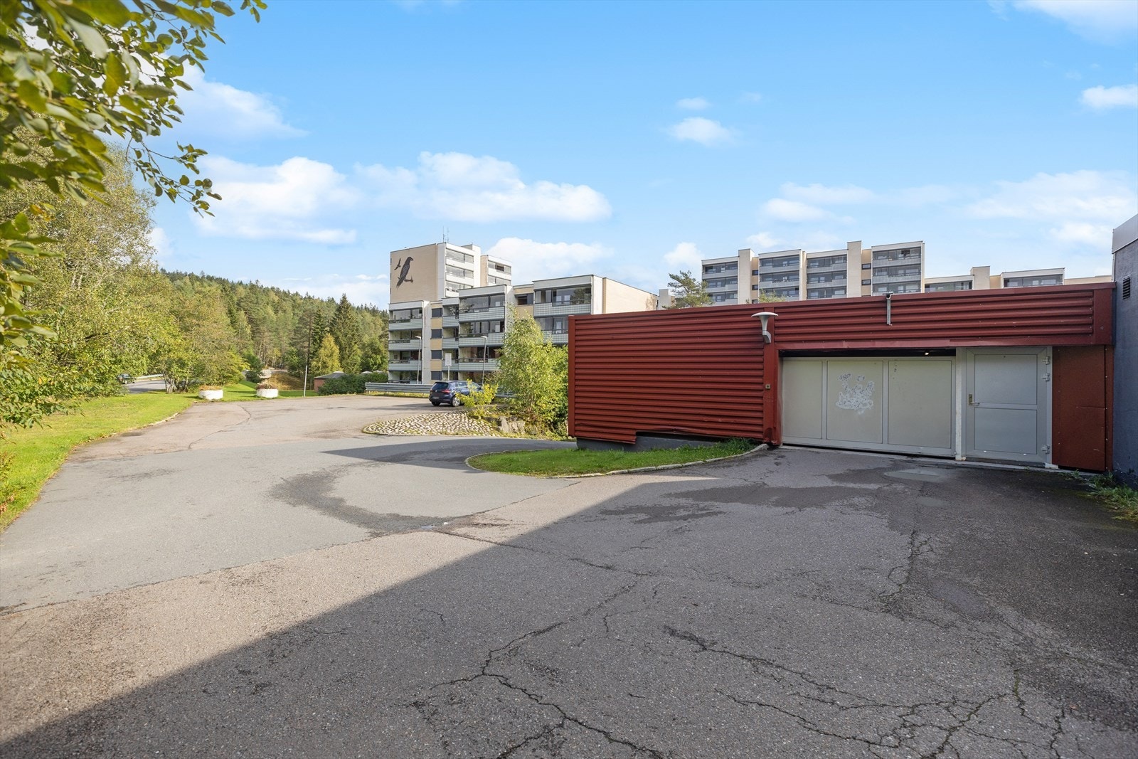 Adkomstområde til borettslaget med parkeringshus og grønne omgivelser i bakgrunnen. Galleribilde
