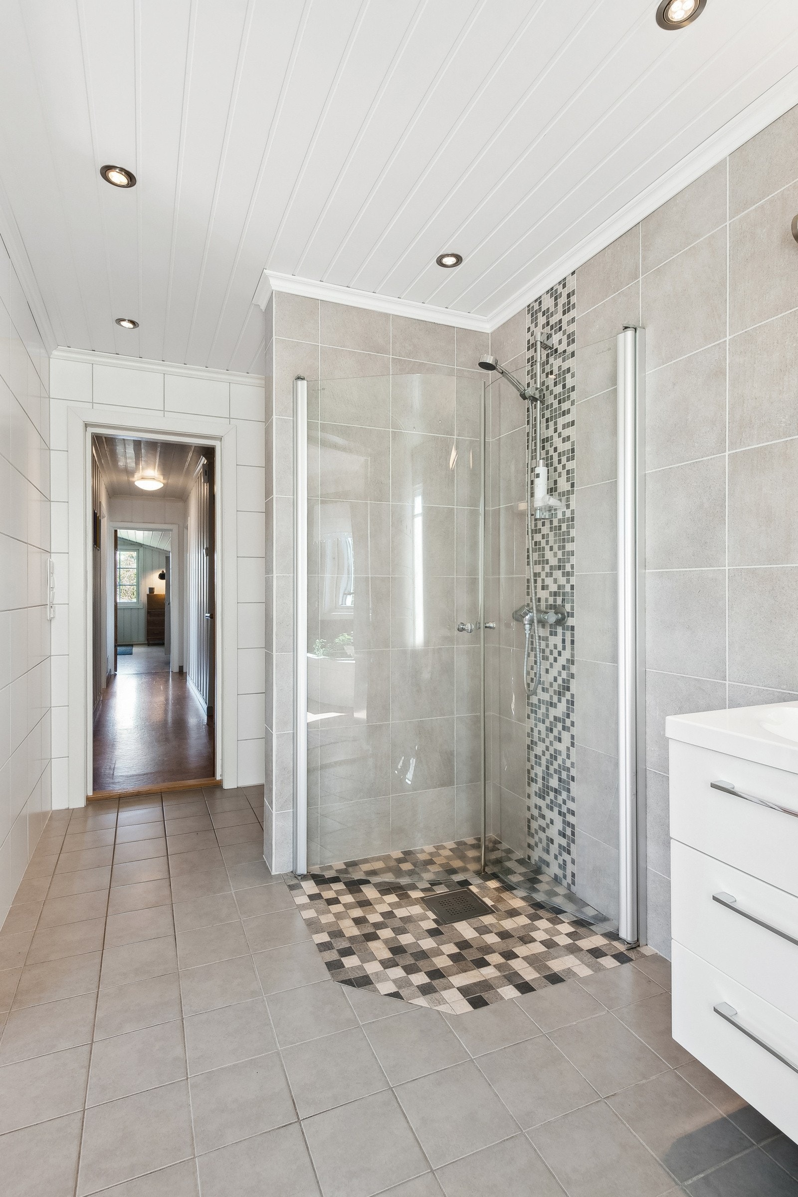 Badet er innredet med veggmontert dusj og dusjvegger, veggmontert wc og baderomsinnredning. Galleribilde