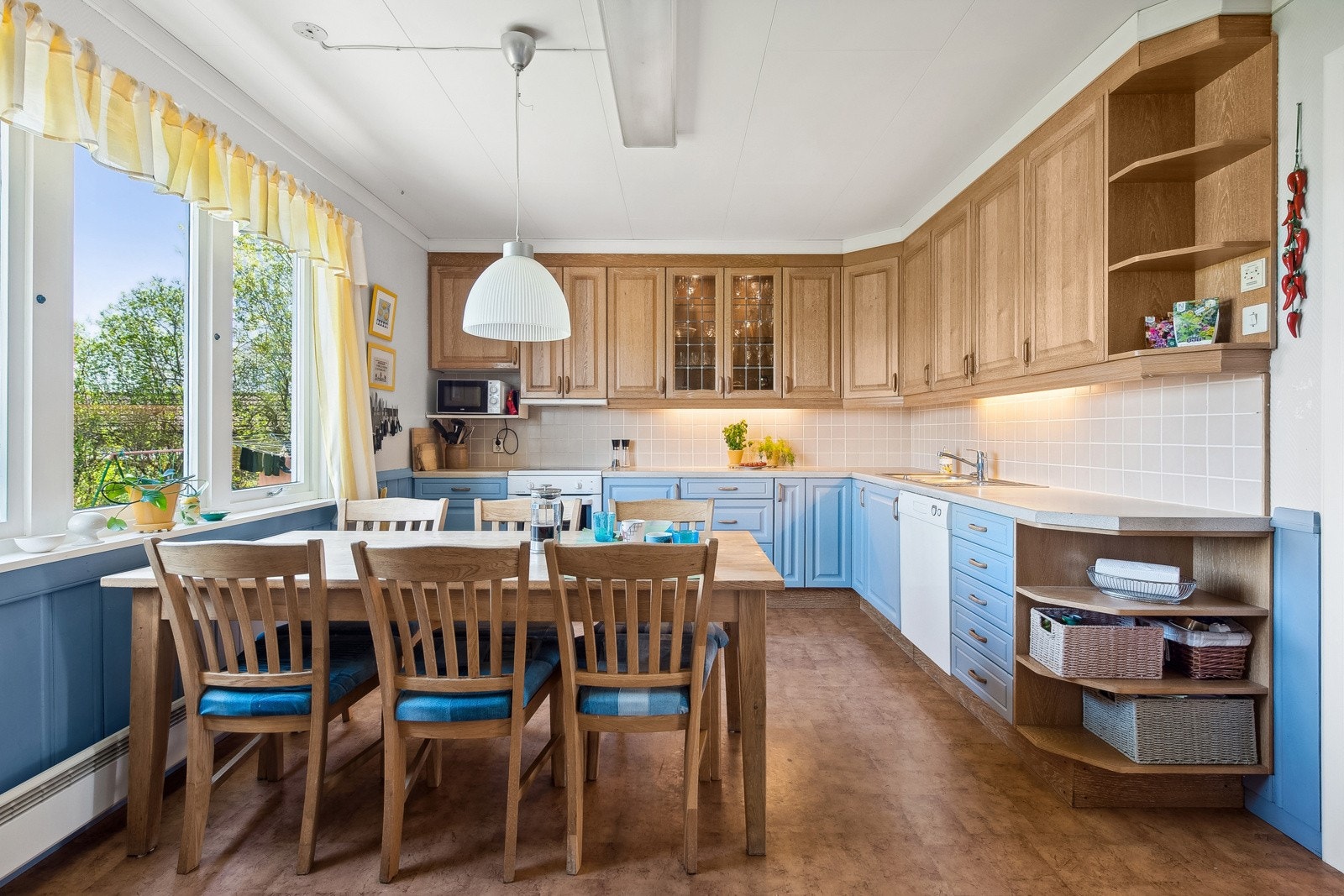 Kjøkkeninnredning i vinkel med plass til frittstående hvitevarer som komfyr, oppvaskmaskin, mikro og kjøleskap. Galleribilde