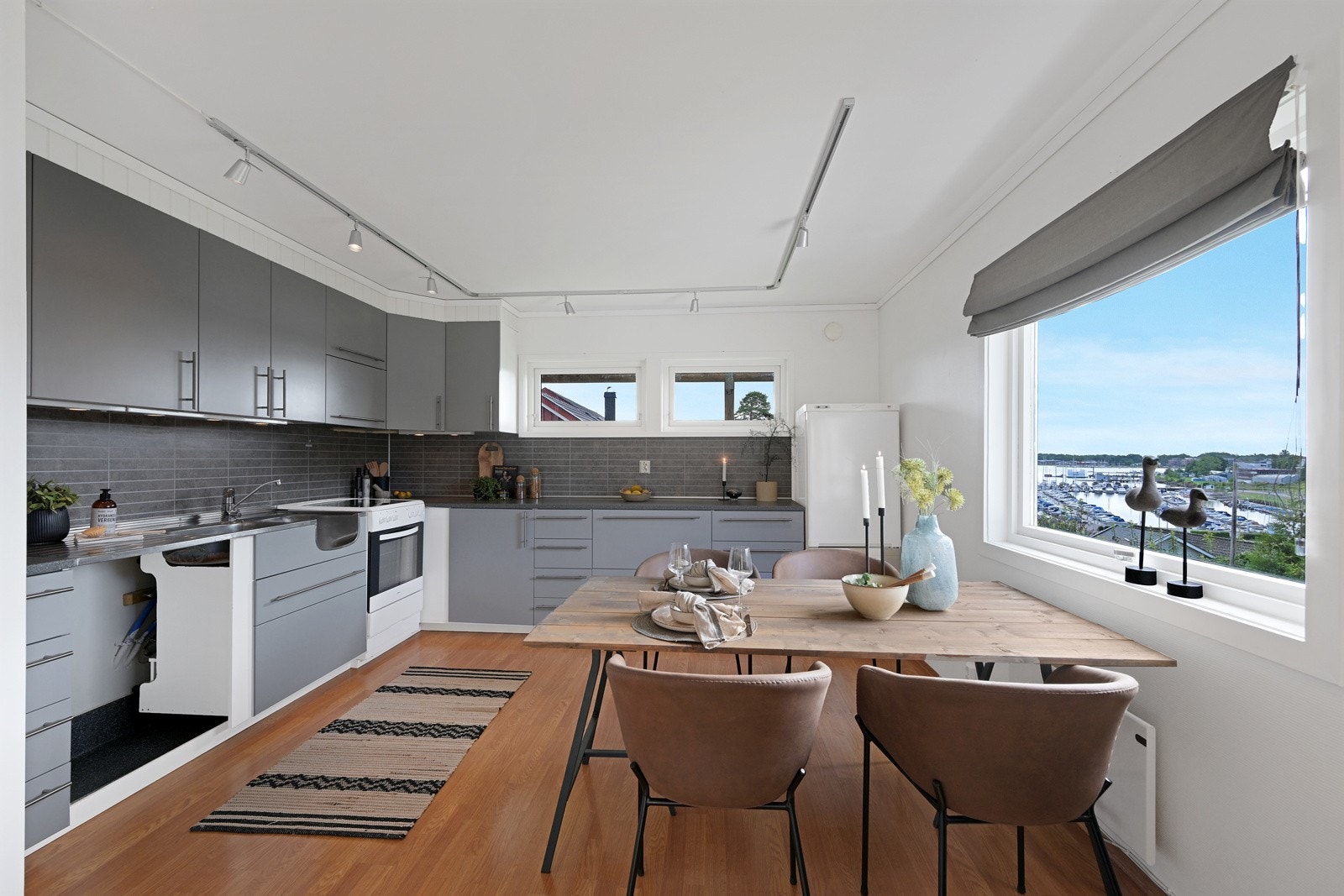 Koselig kjøkken med gråmalt innredning og kjøkkenbord med fin utsikt Galleribilde
