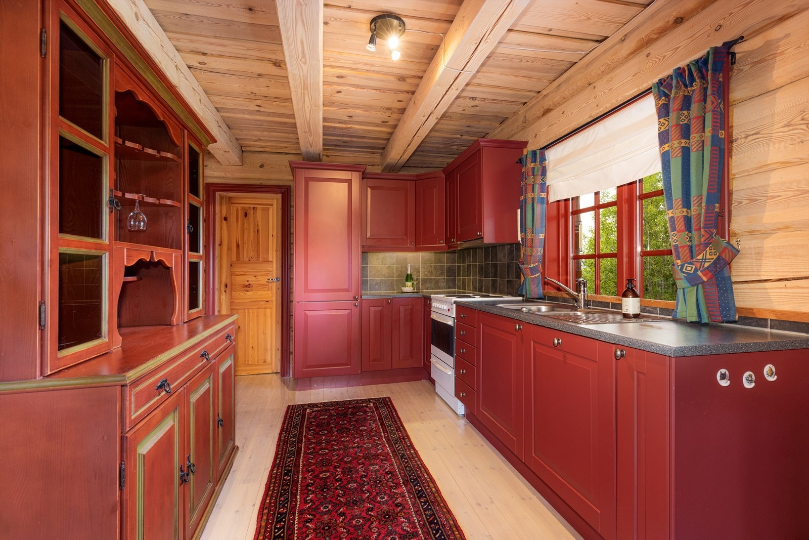 Her er det plass til alt man måtte trenge på hytta, og det er godt med lysinnslipp fra vindu ved kjøkkenvasken. Kjøkkenet har integrerte hvitevarer som oppvaskmaskin og kjøleskap, samt frittstående komfyr. Galleribilde