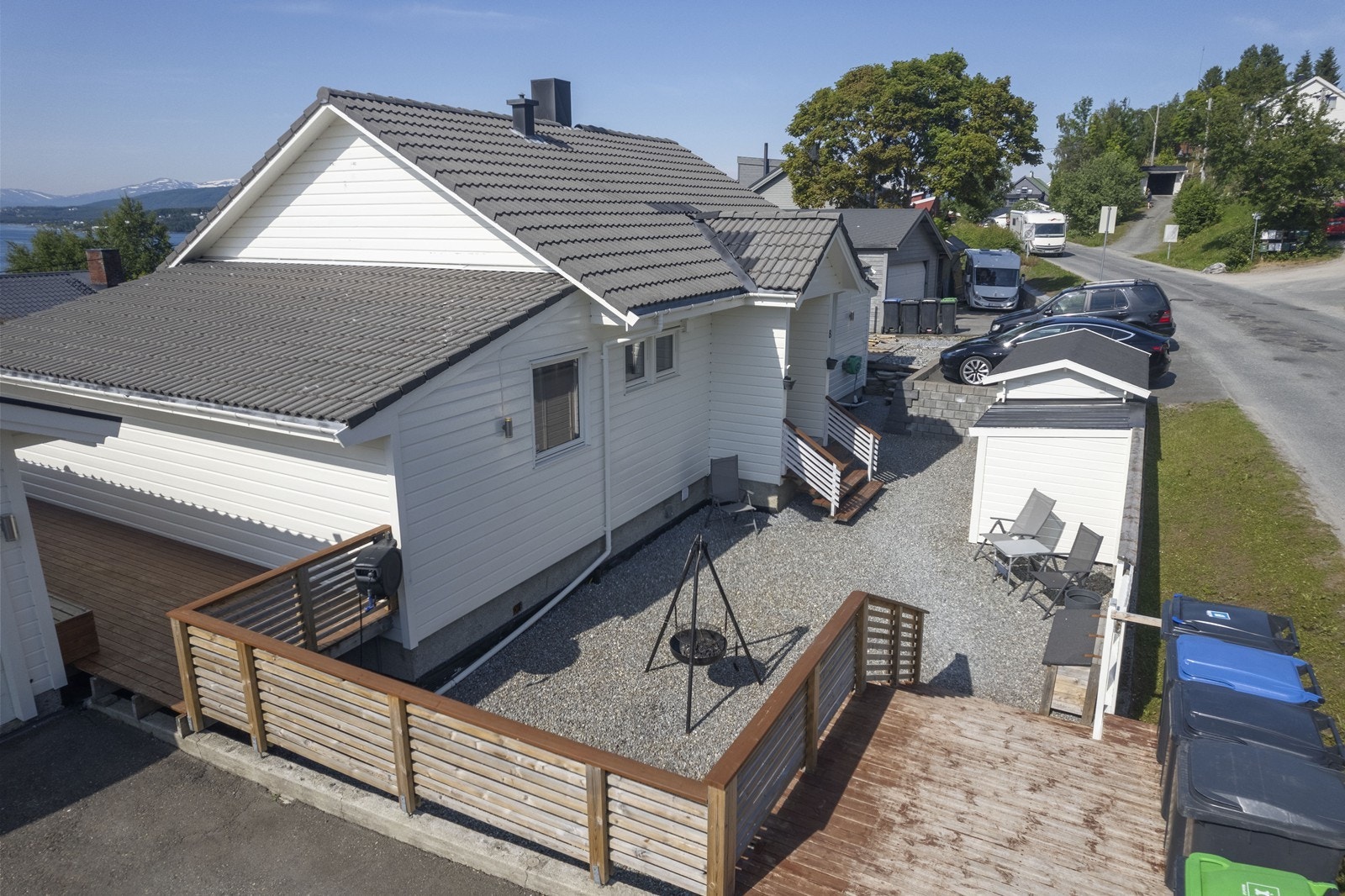 Pent opparbeidet uteområde med terrasser, asfaltert og gruslagt gårdsplass, gressplen og beplantninger Galleribilde