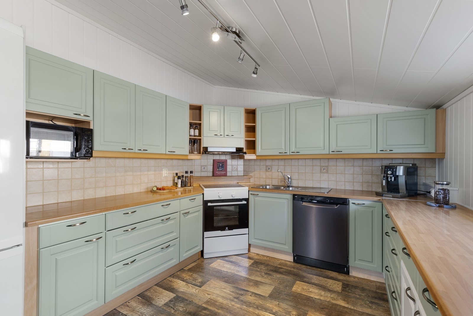 Romslig kjøkken i pene farger med god plass i skap og på benk Galleribilde