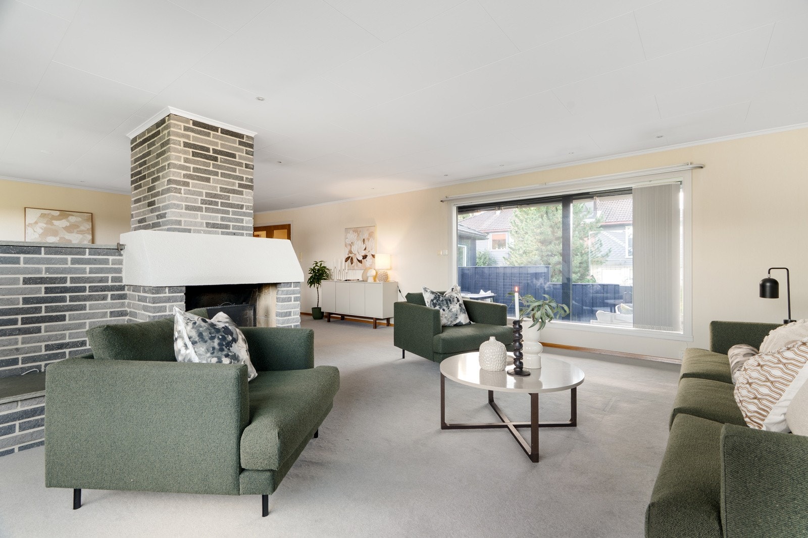 En koselig peis deler rommet inn i naturlige soner, noe som gir både hygge og fleksibilitet i møbleringen. Galleribilde