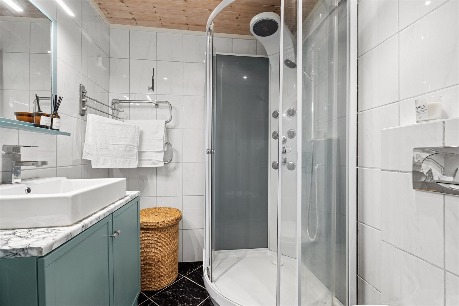 Innredet med dusjkabinett i dusjhjørnet, veggmontert wc og baderomsinnredning med servant og speil med belysning. Galleribilde