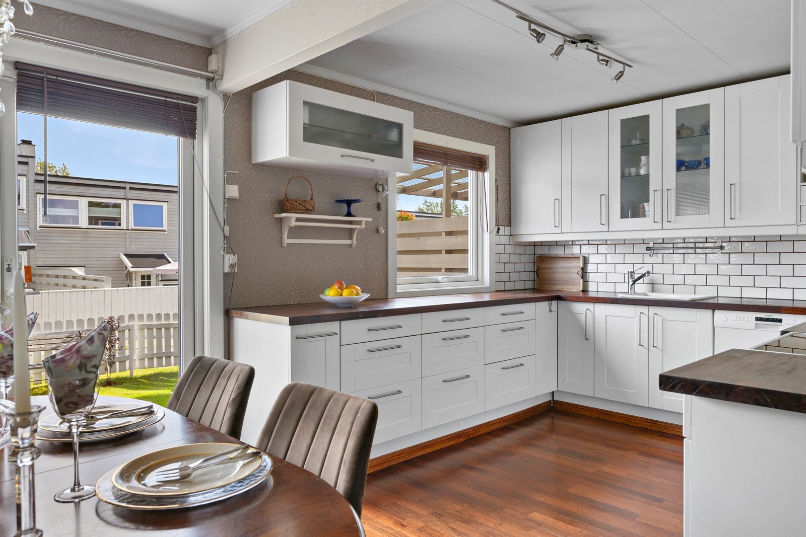 Pent kjøkken i egen sone med lys, profilert innredning, fliser over benkeplaten og vindu ut mot hagen. Galleribilde