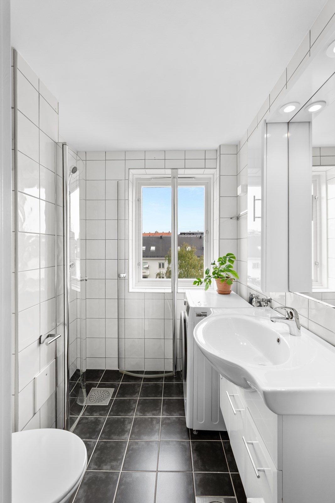 Badet har tidløse fliser, klosett og opplegg for vaskemaskin/tørketrommel. Galleribilde