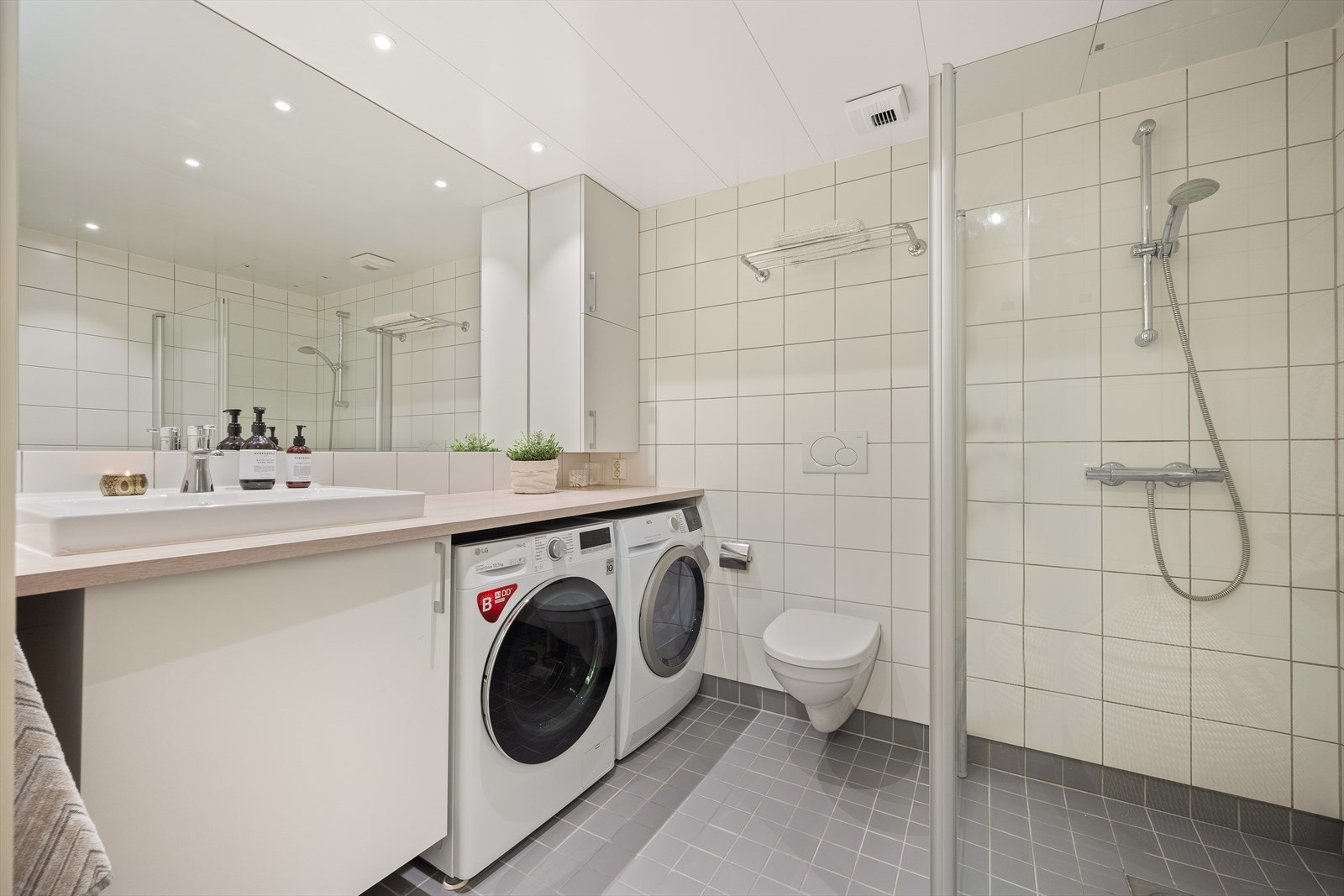 Romslig bad fra 2013 med flislagte overflater, innfelte downlights i himling og elektrisk gulvvarme. Opplegg og plass til både vaskemaskin og tørketrommel. Galleribilde