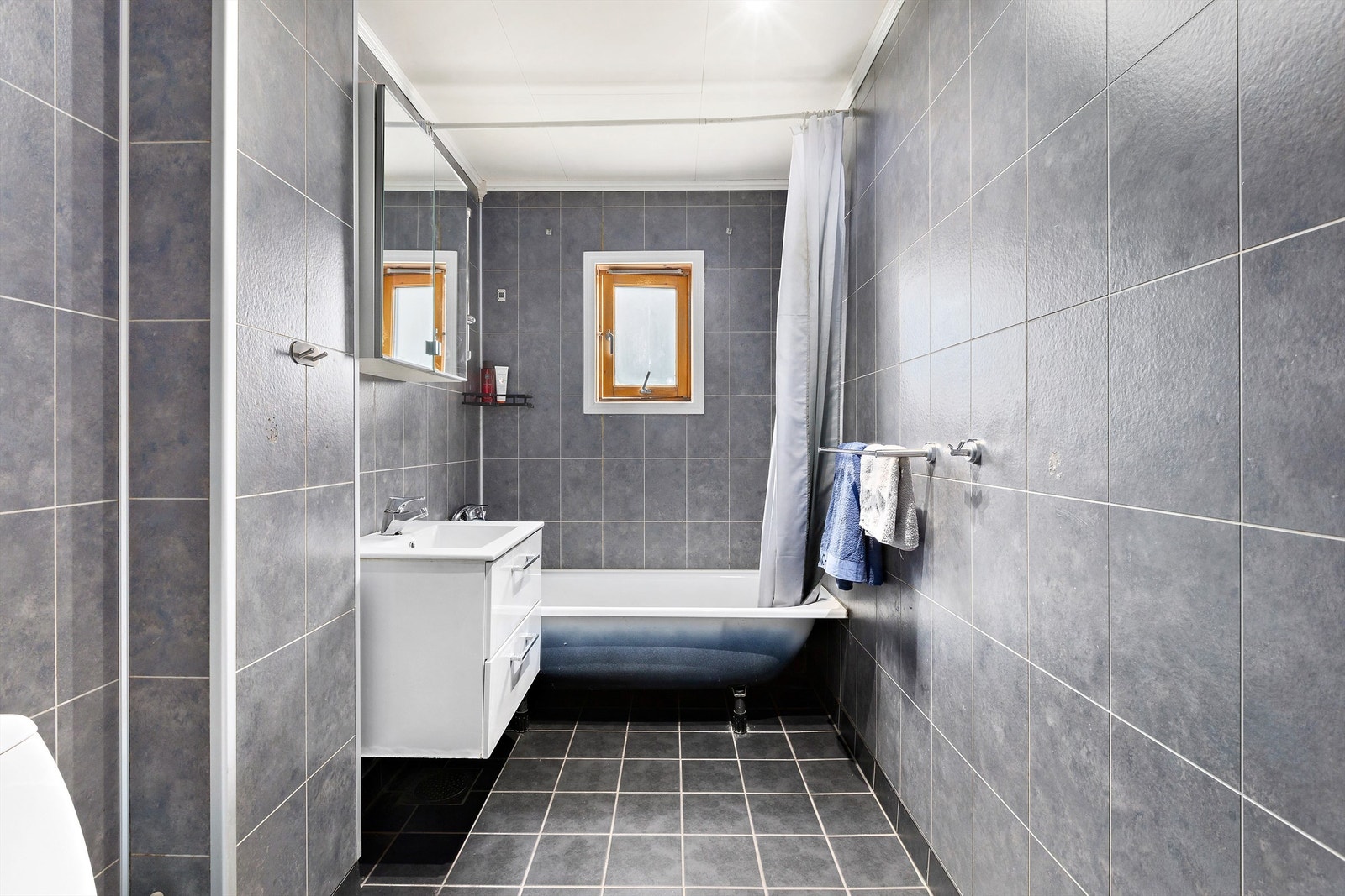 Rommet er utstyrt med badekar, gulvmontert toalett og baderomsinnredning Galleribilde