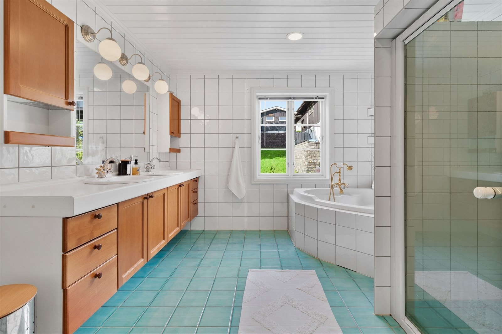 Helfliset baderom innredet med badekar, dusj, toalett og dobbel servant. Galleribilde