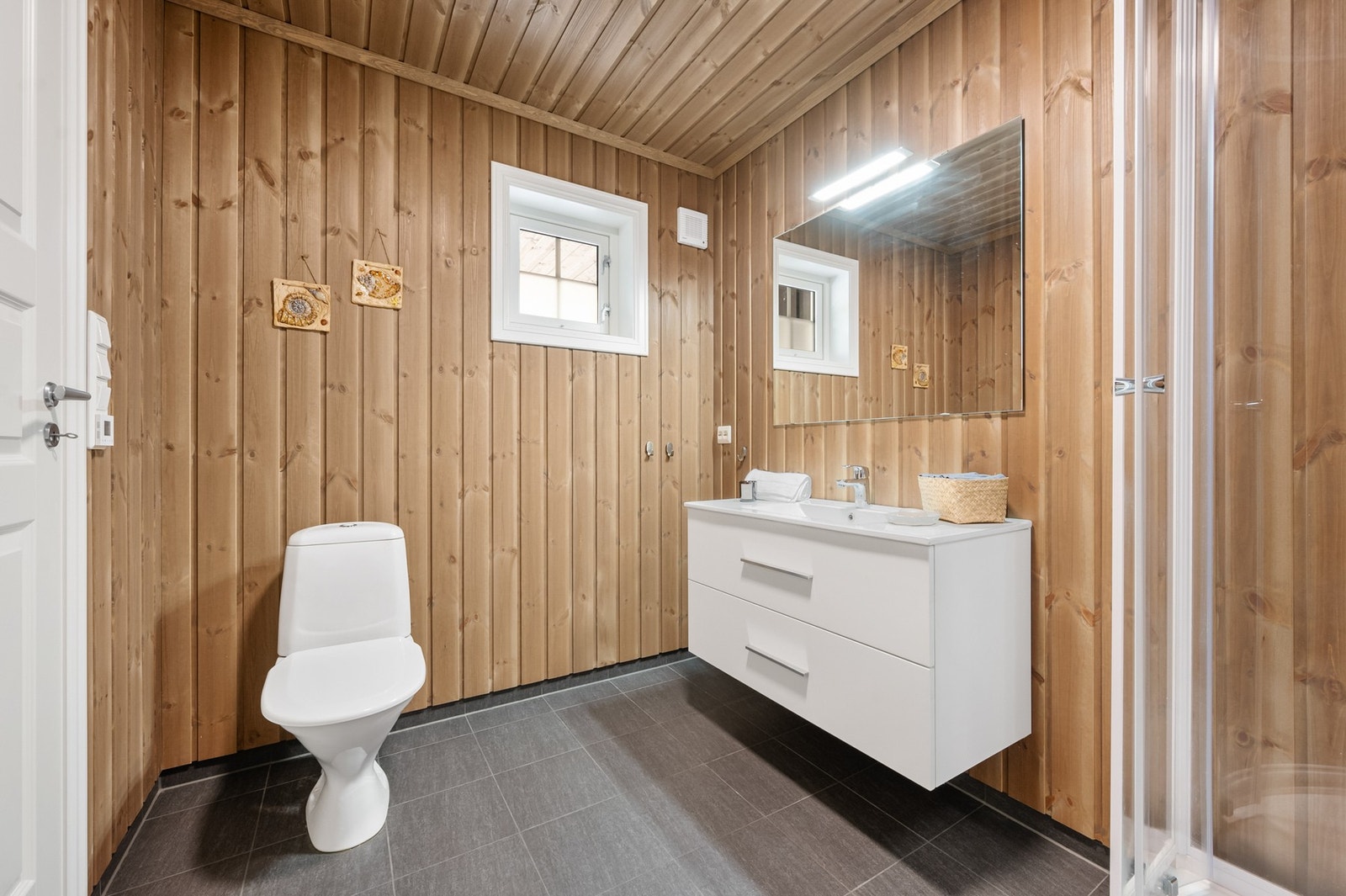 Baderommet er utstyrt med toalett, stor servant, dusj kabinett og opplegg for vaskemaskin. Galleribilde