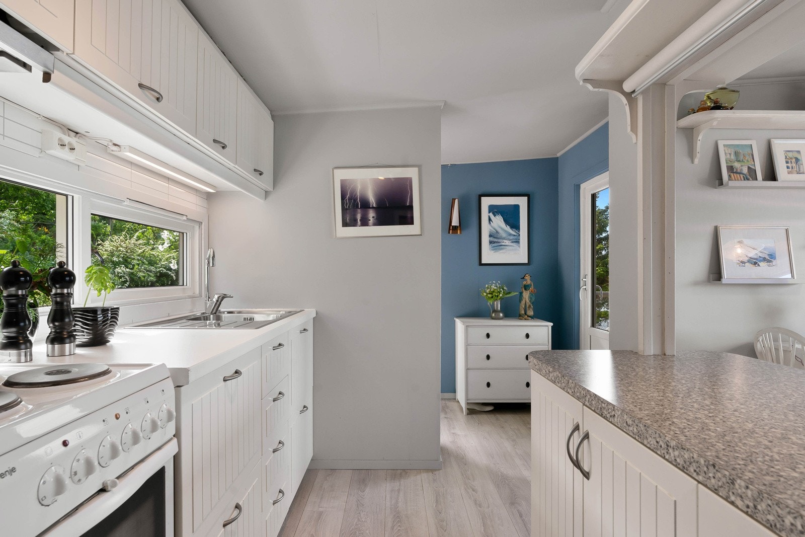 Veggen bak har fliser. Det er ellers tilrettelagt plass for kjøleskap og komfyr, samt over komfyren er det montert ventilator. Galleribilde