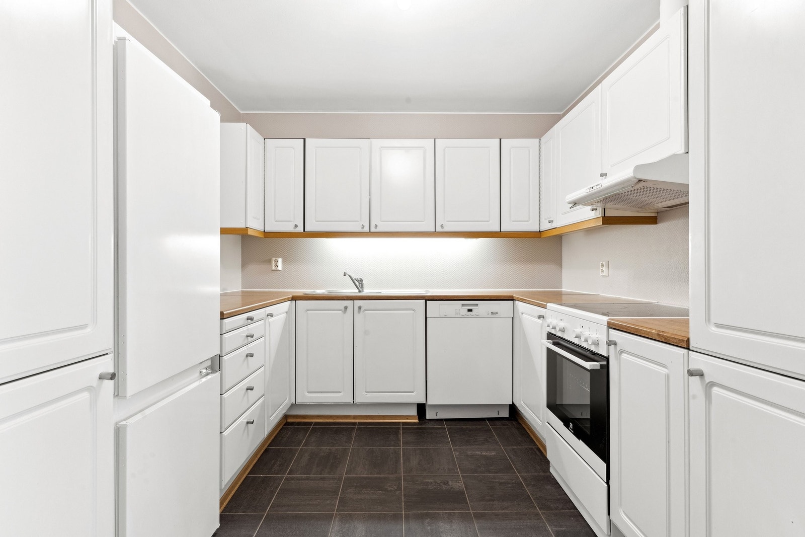 Kjøkken fra byggeår med hvite fronter og benkeplater av tre Galleribilde