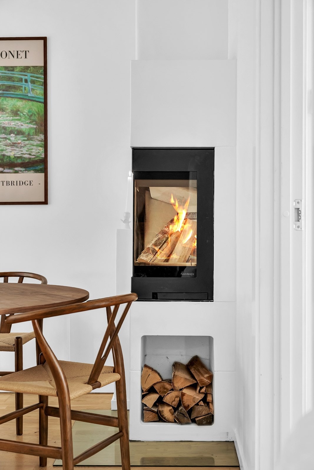 Moderne peis med integrert vedholder gir både varme og praktisk oppbevaring Galleribilde